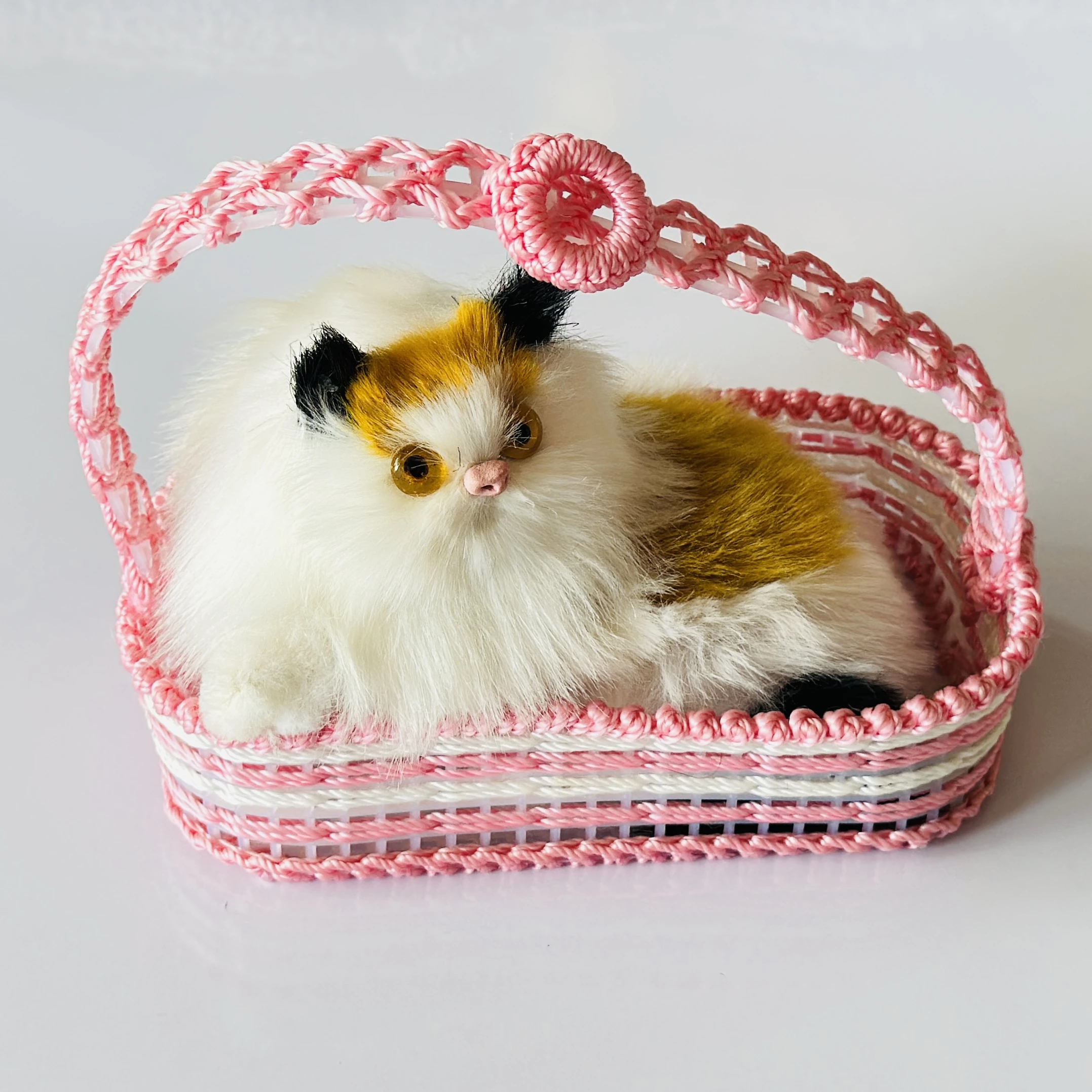 Decorative showpiece featuring a plush cat sitting inside a pink woven basket