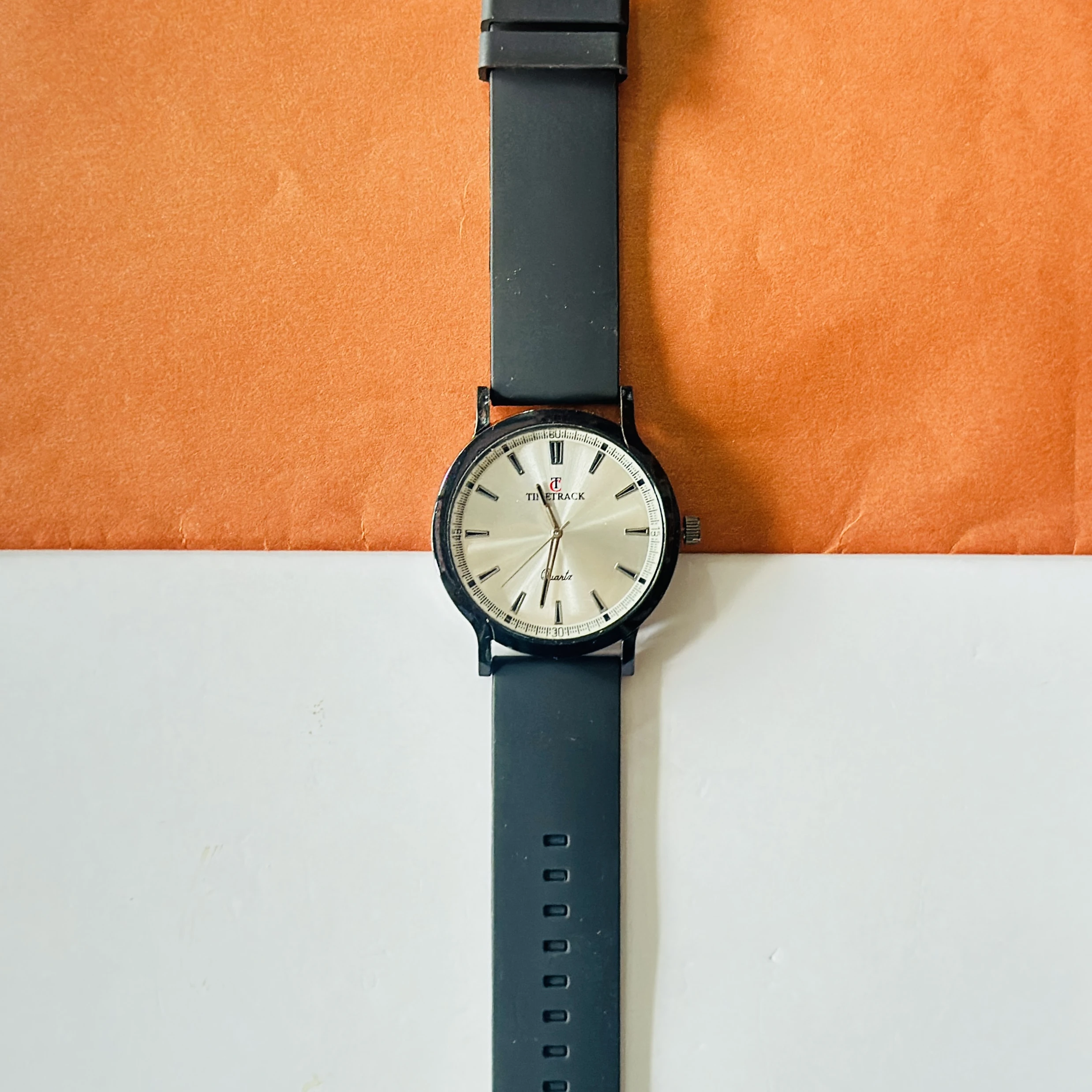 Timitrack brand quartz analog wristwatch with a silver-toned dial and a black silicone strap.