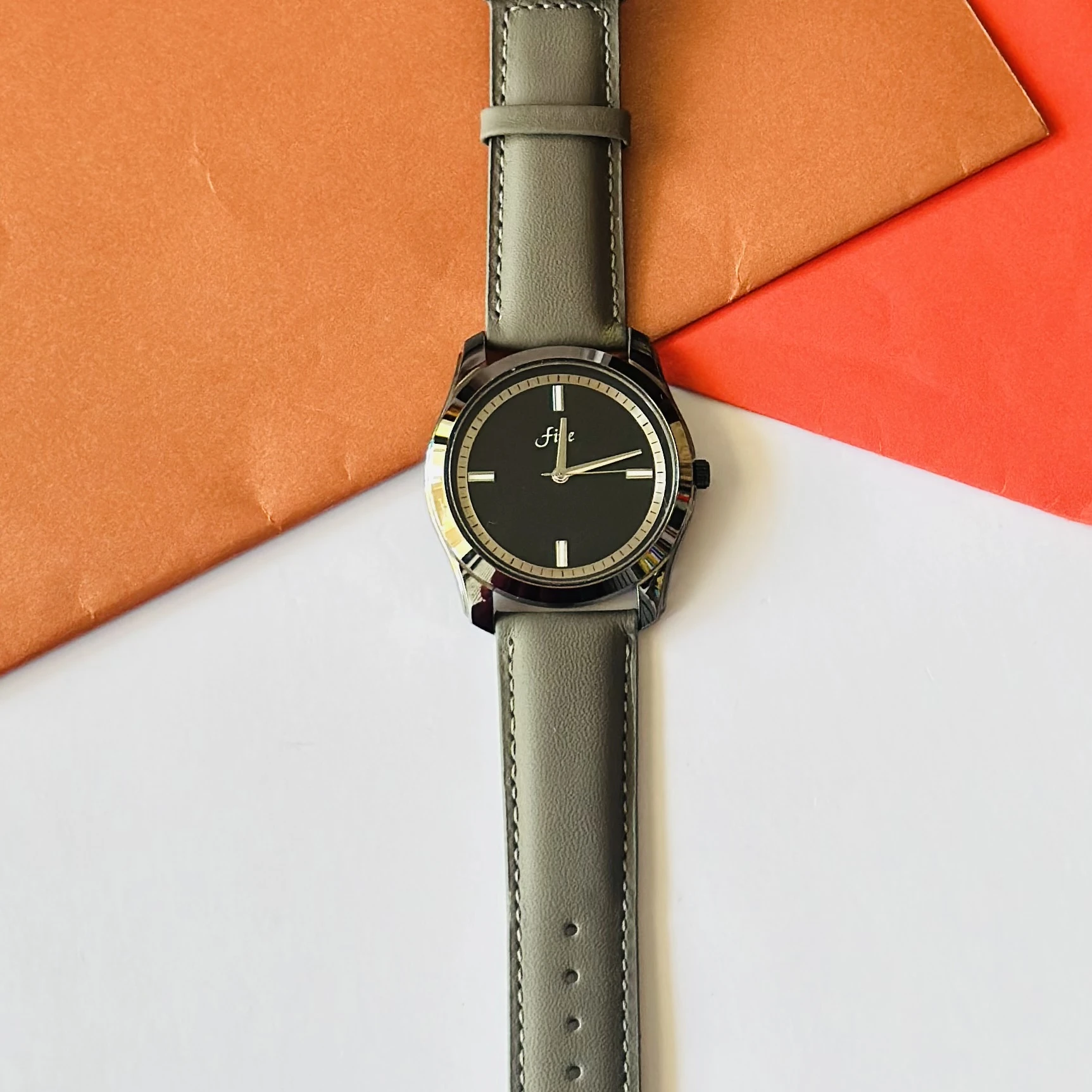 watch with a gray leather strap and a black dial.