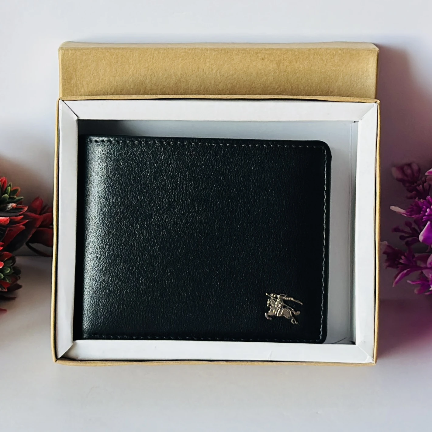 Black bifold leather wallet with a metal logo accent.