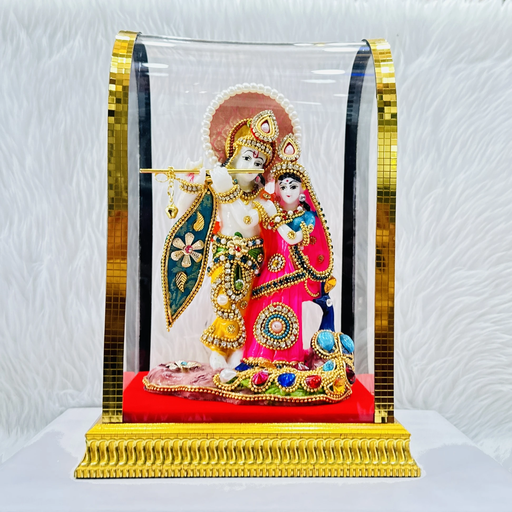 Decorative Radha Krishna statue enclosed in a protective glass dome.