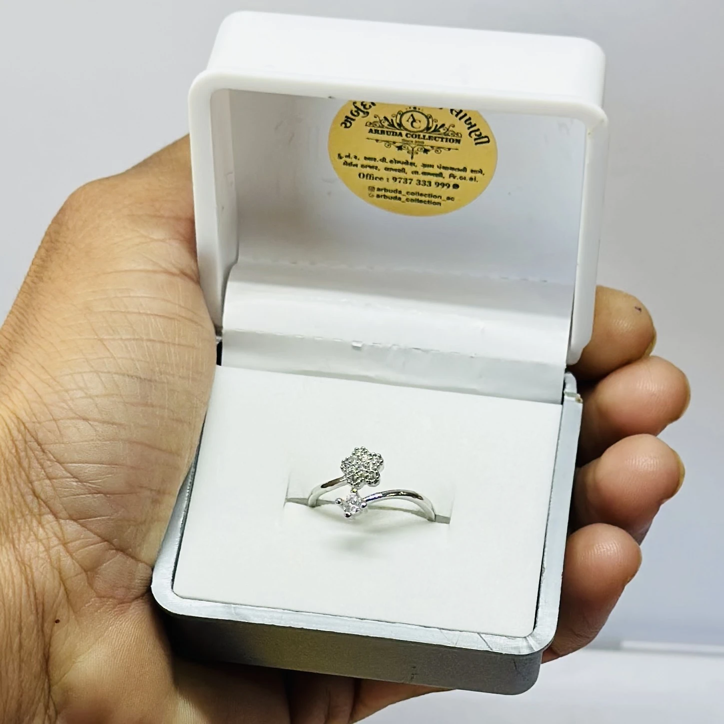 an adjustable silver-toned, stone-studded finger ring with a flower design.
