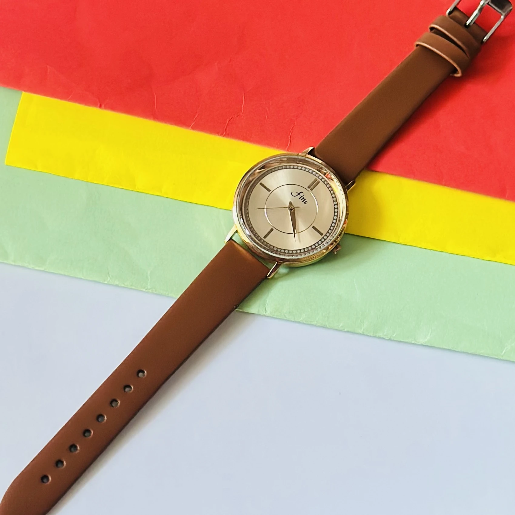 Gold tone analog wrist watch with a brown leather strap