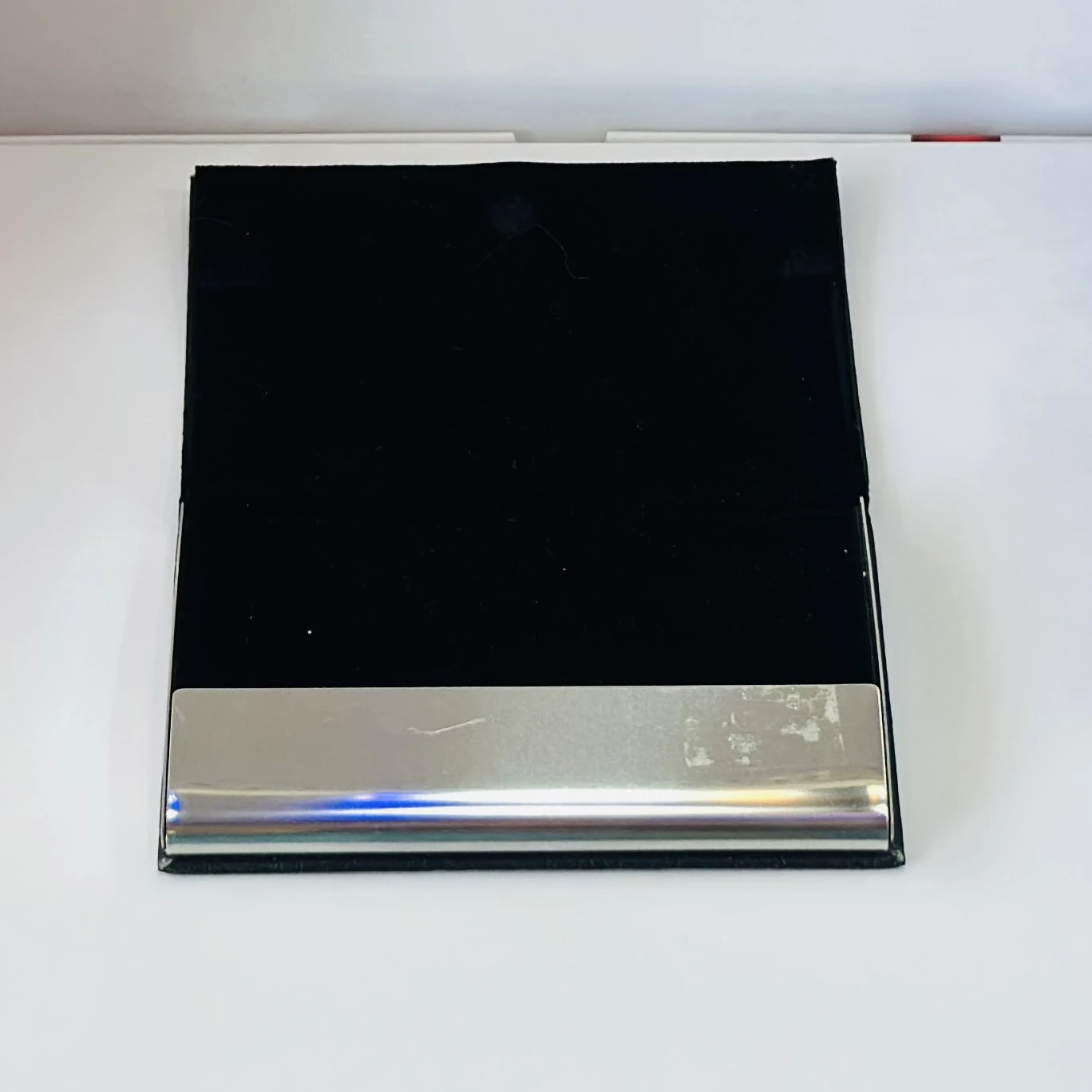 Black faux leather and metal business card holder.