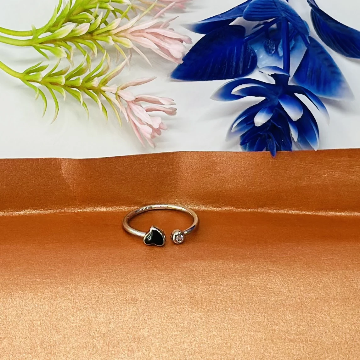 An adjustable silver-toned ring with a black heart and a clear stone accent.