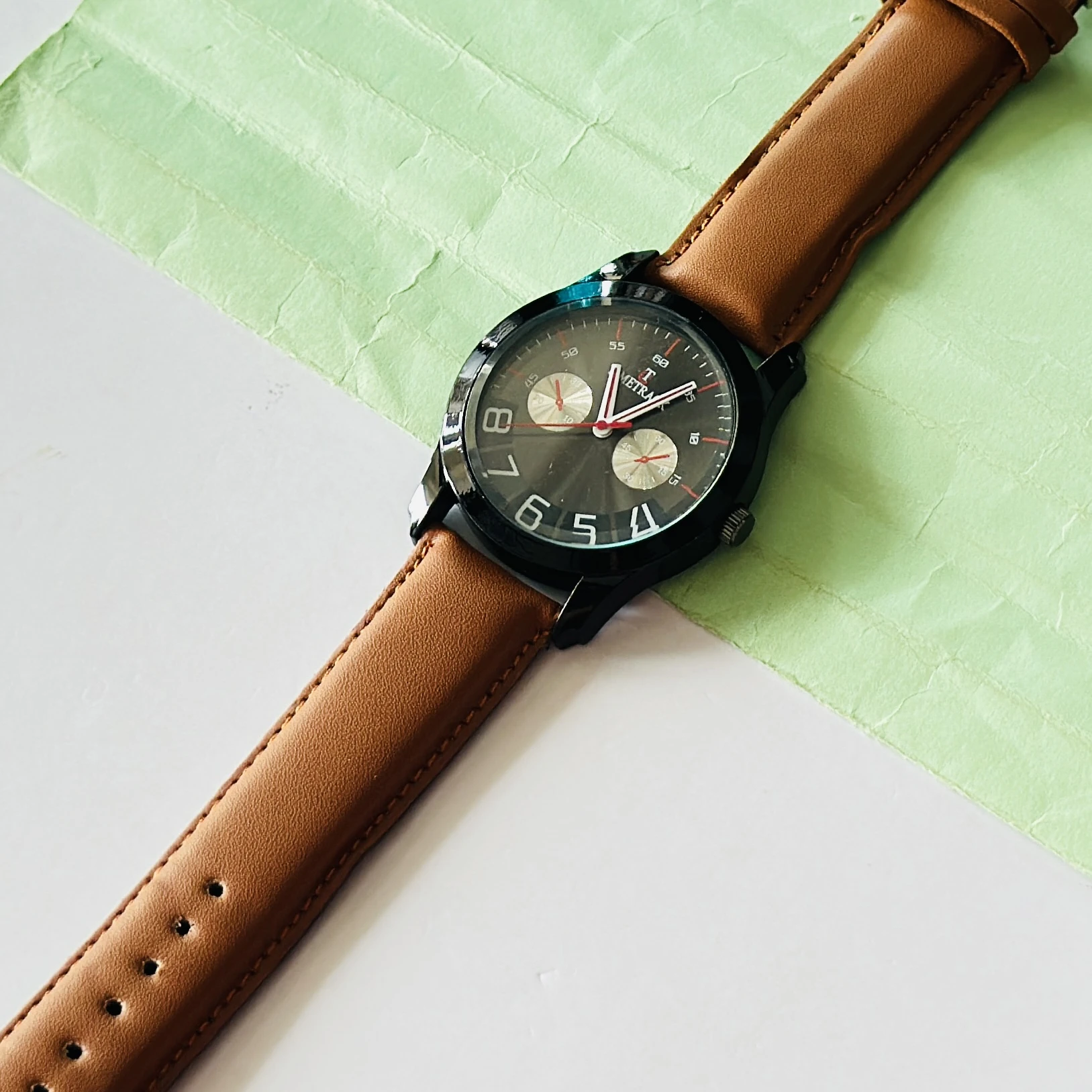 Titan Quartz Analog watch with a brown leather strap and a black dial.