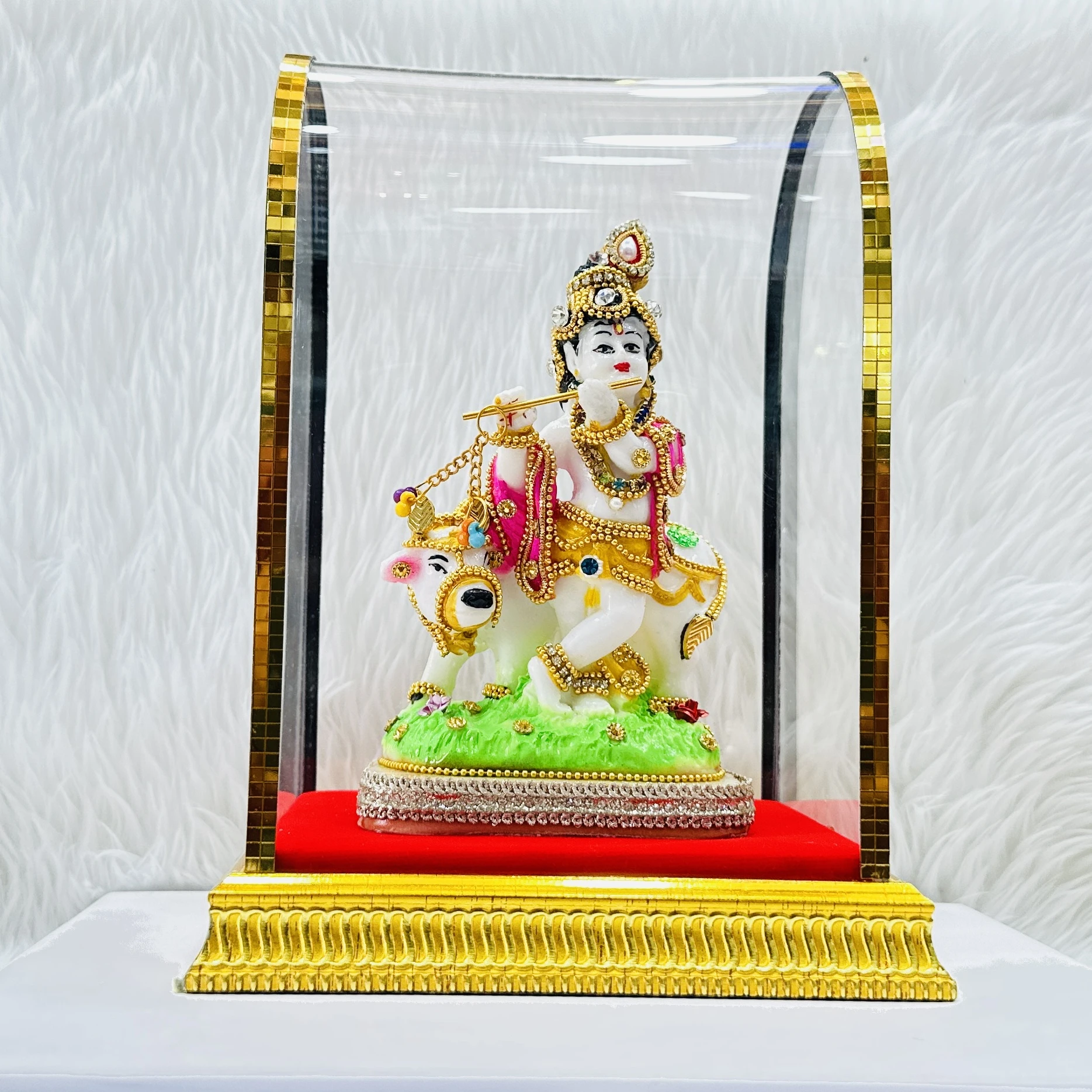 Lord Krishna and a cow housed within a protective glass case.