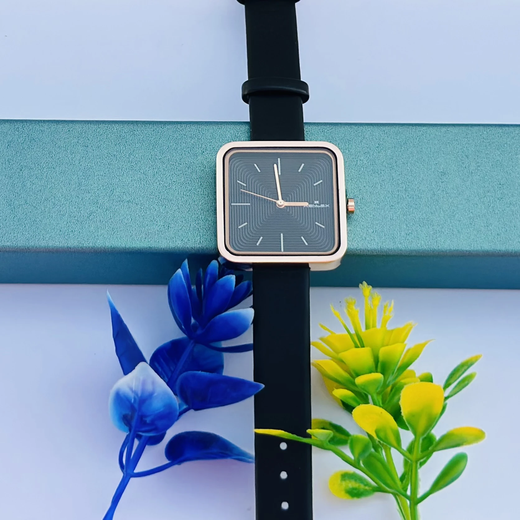 square-dial women's watch with a black strap and rose gold-tone case.