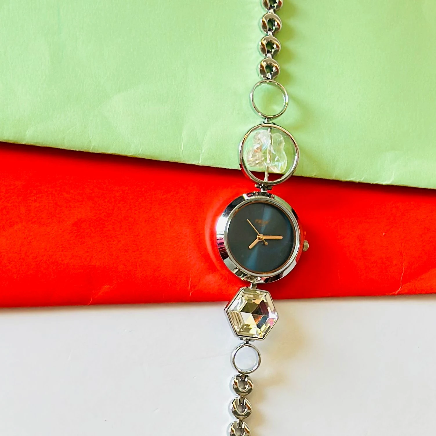 analog watch for women with a blue dial and a metal strap featuring crystal-studded geometric links.