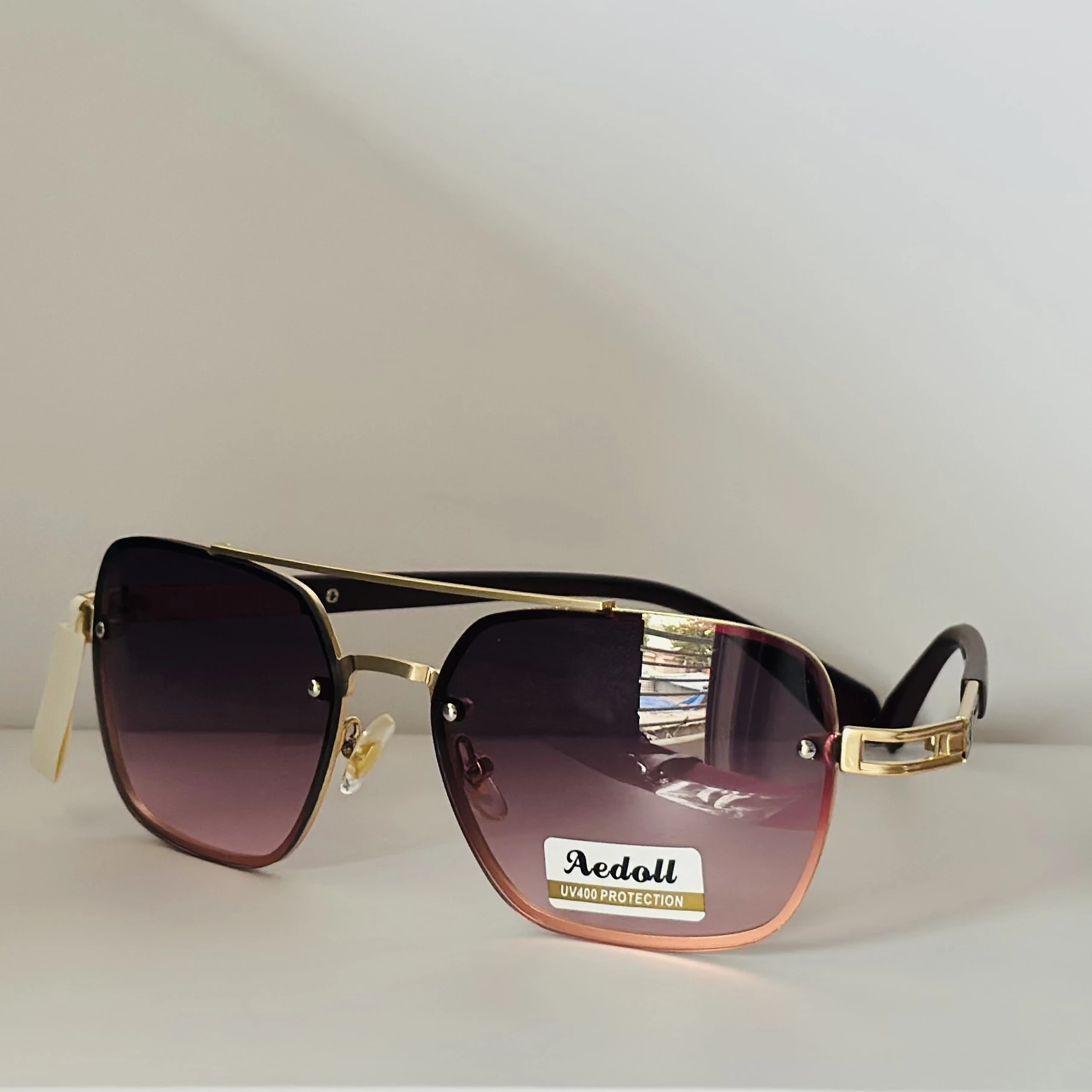 pair of Aedoll Goggle sunglasses with a gold metal frame and pink gradient lenses.