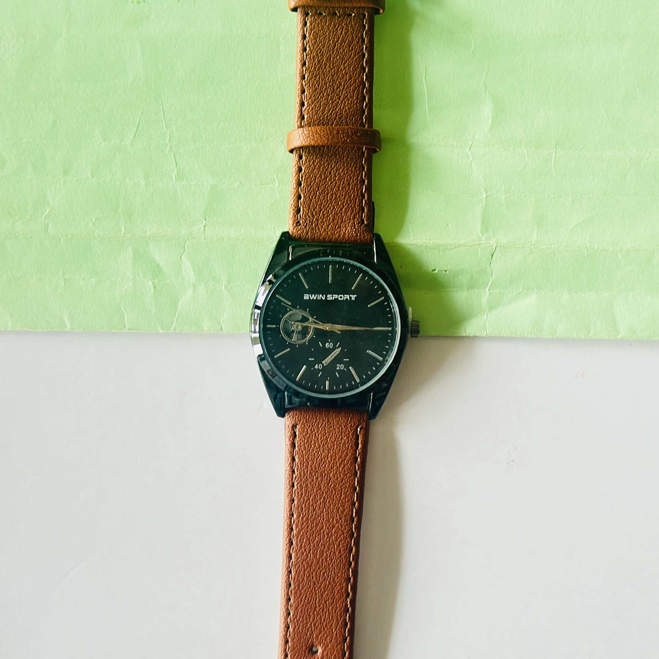 Carlington analog watch with a brown faux leather strap and a black dial.