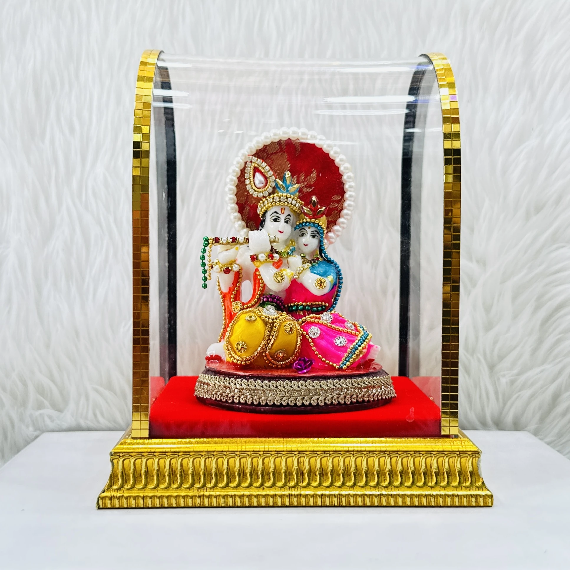 Radha Krishna statue enclosed in a protective glass case.
