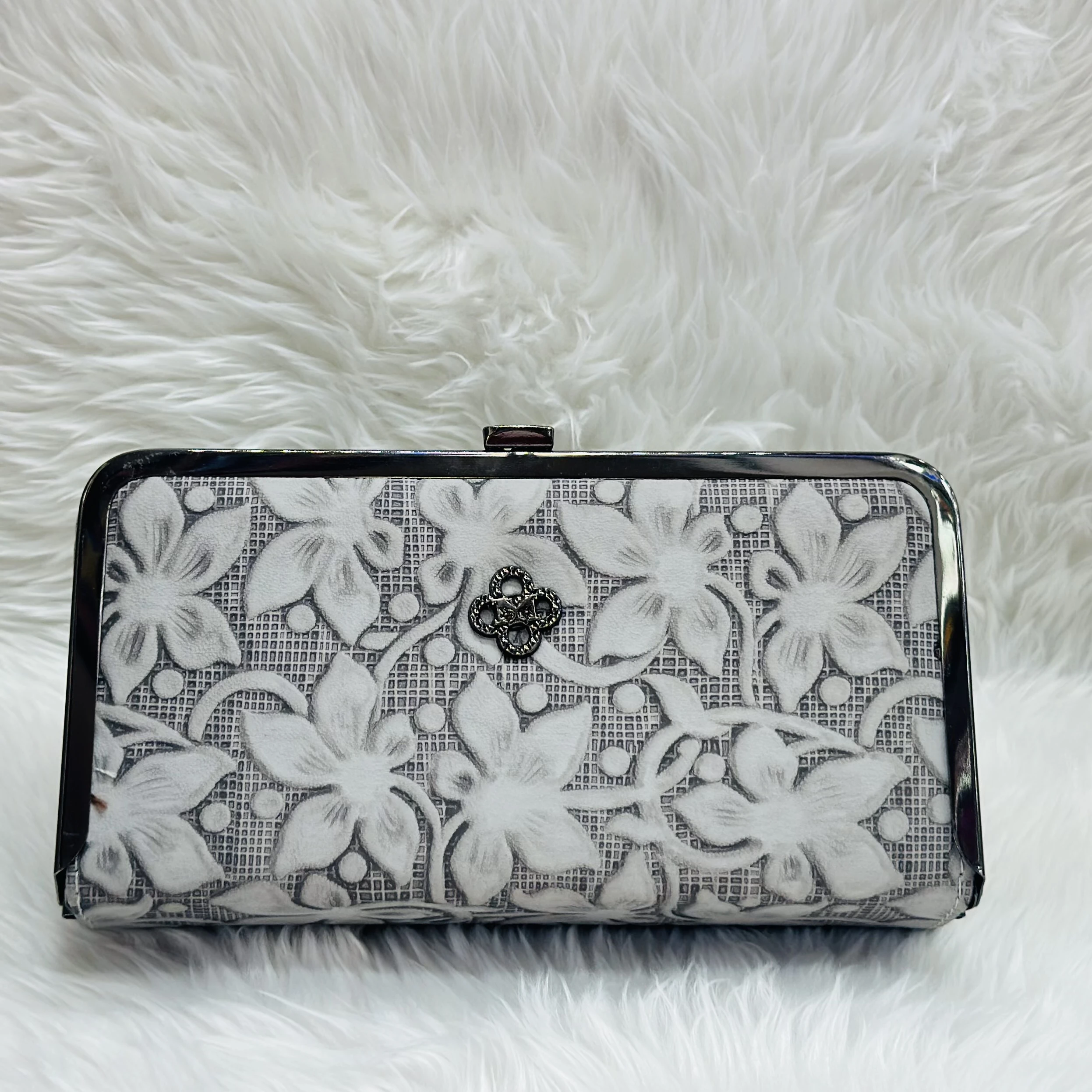 Embellished box clutch bag with a black metal frame and a floral pattern.