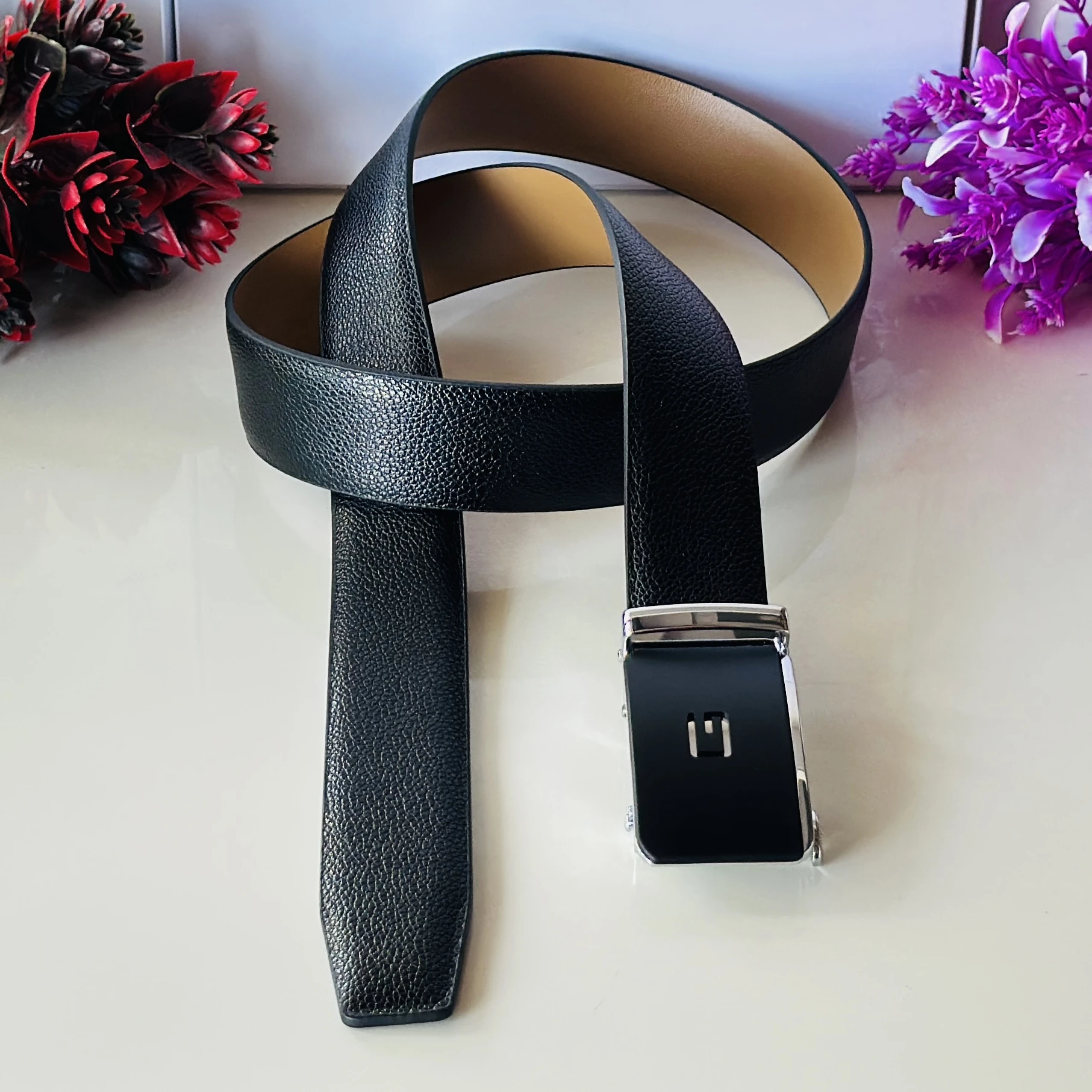 Black leather belt with an automatic/ratchet buckle.