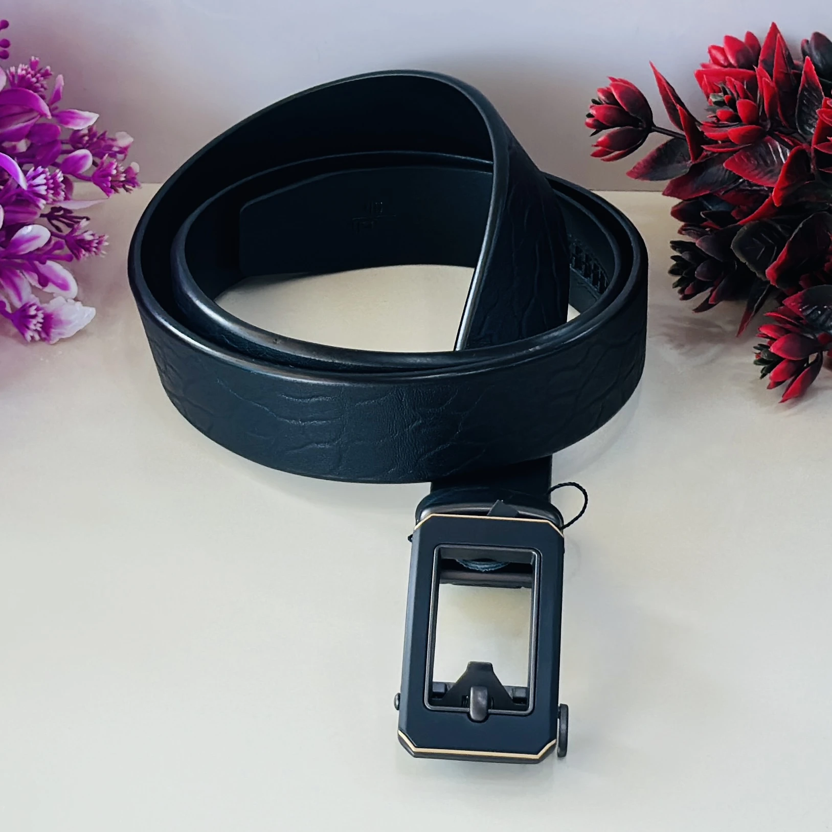 Black leather belt with a metal plaque buckle.