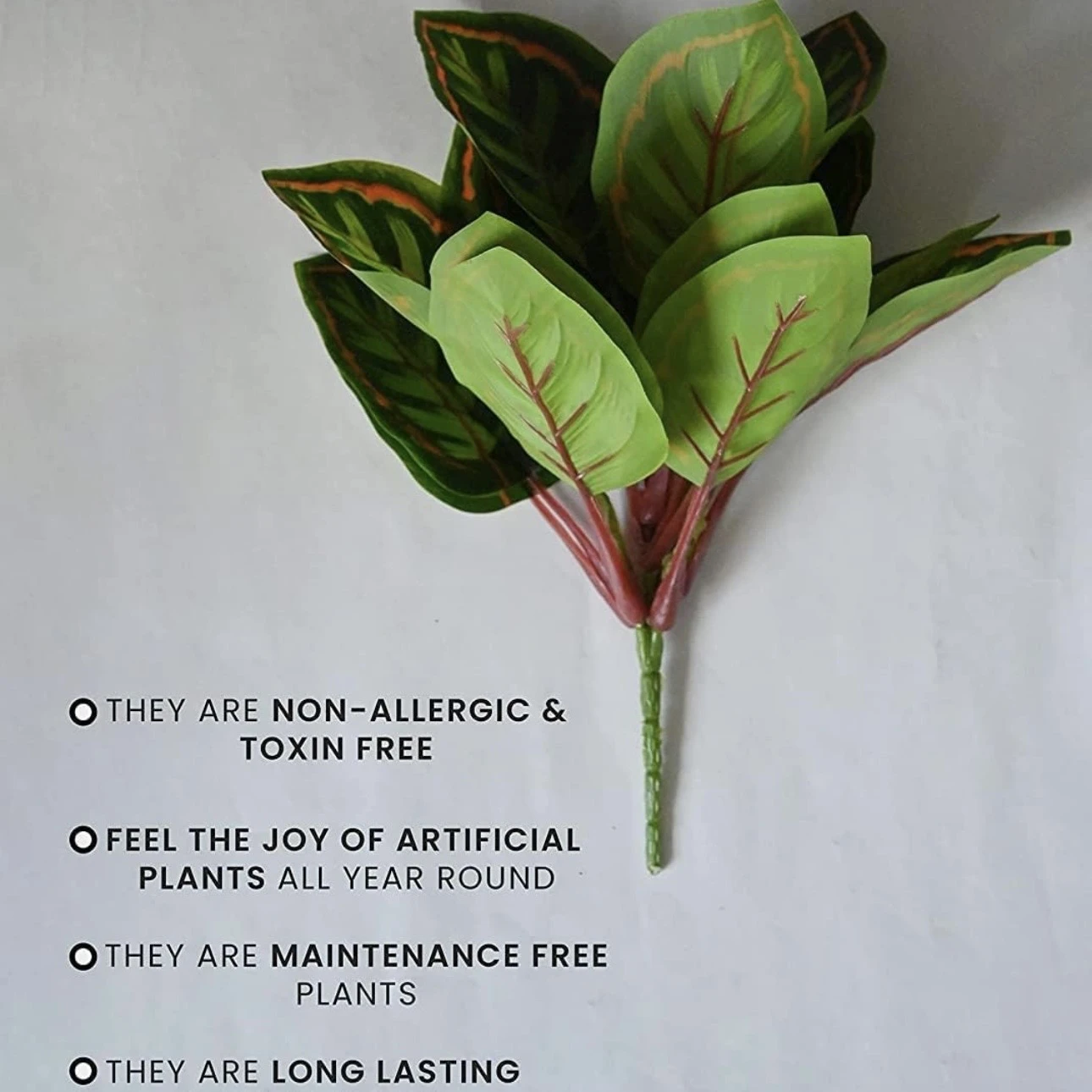An artificial Calathea plant in a black plastic pot.