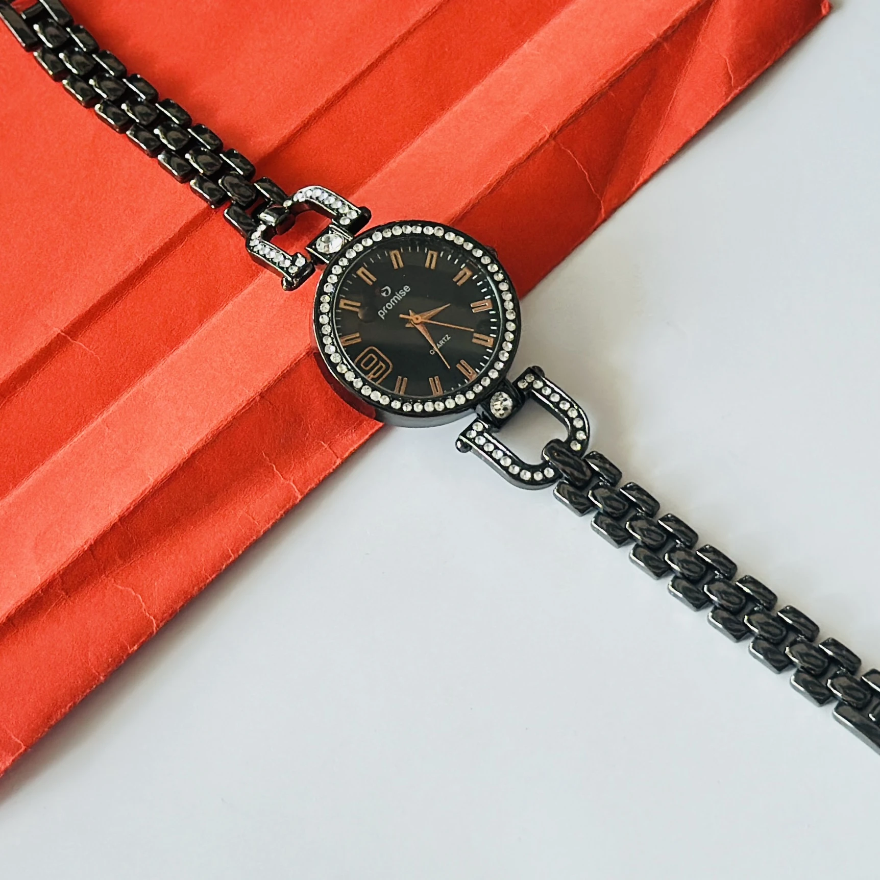 women's bracelet watch featuring a black dial and a diamond-studded bezel.