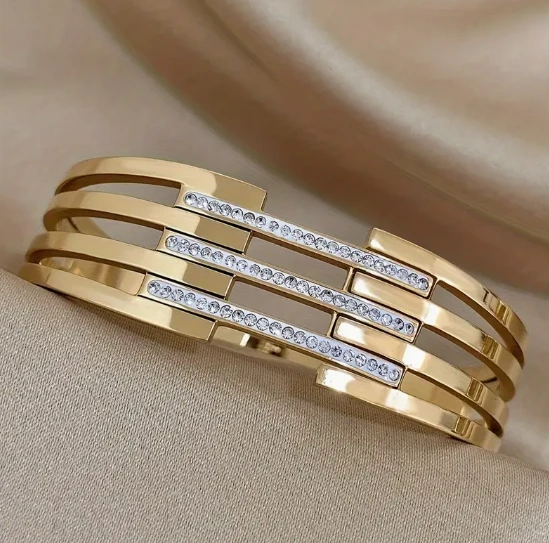 Gold -tone stainless steel hinge cuff bracelet featuring rhinestone accents