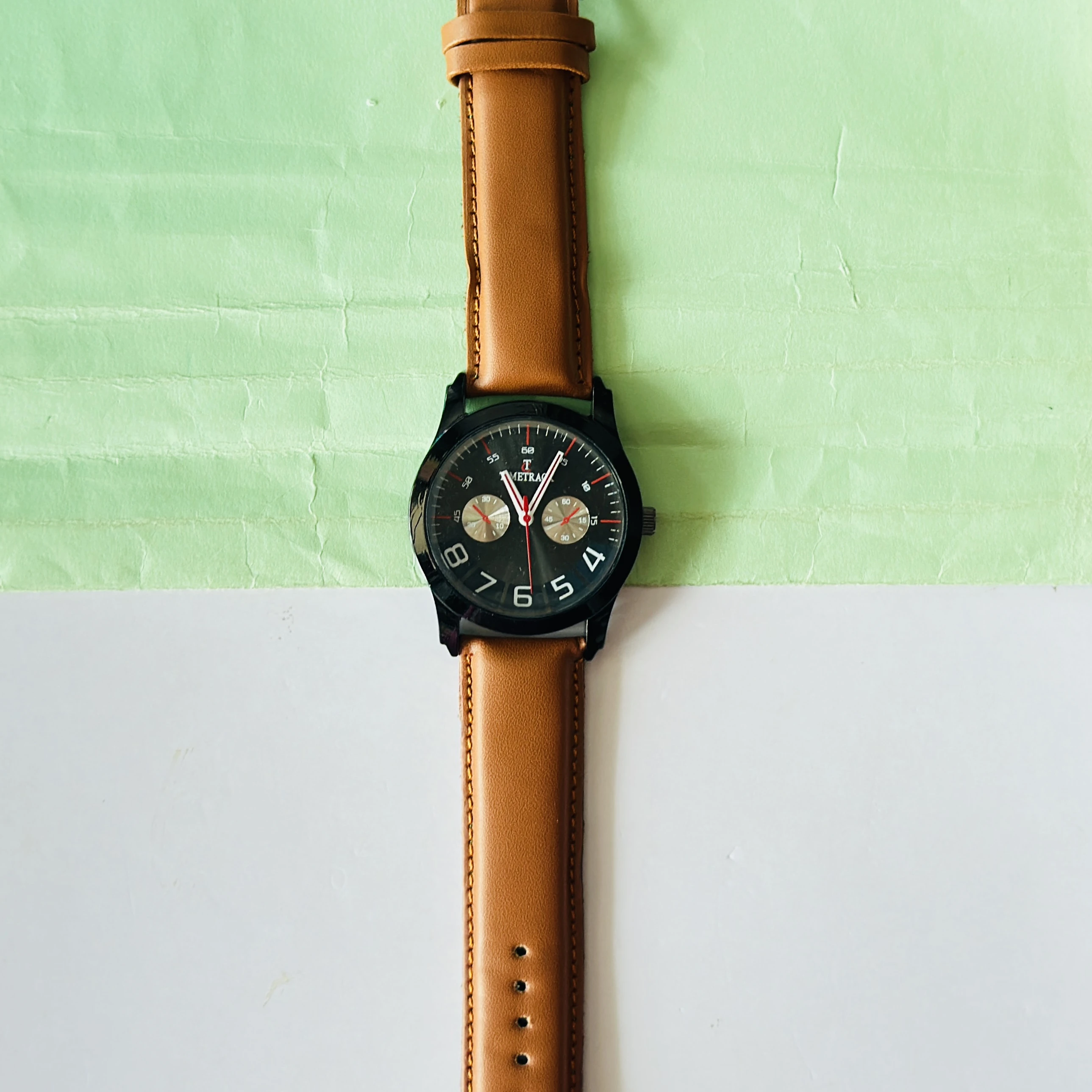 Titan Quartz Analog watch with a brown leather strap and a black dial.