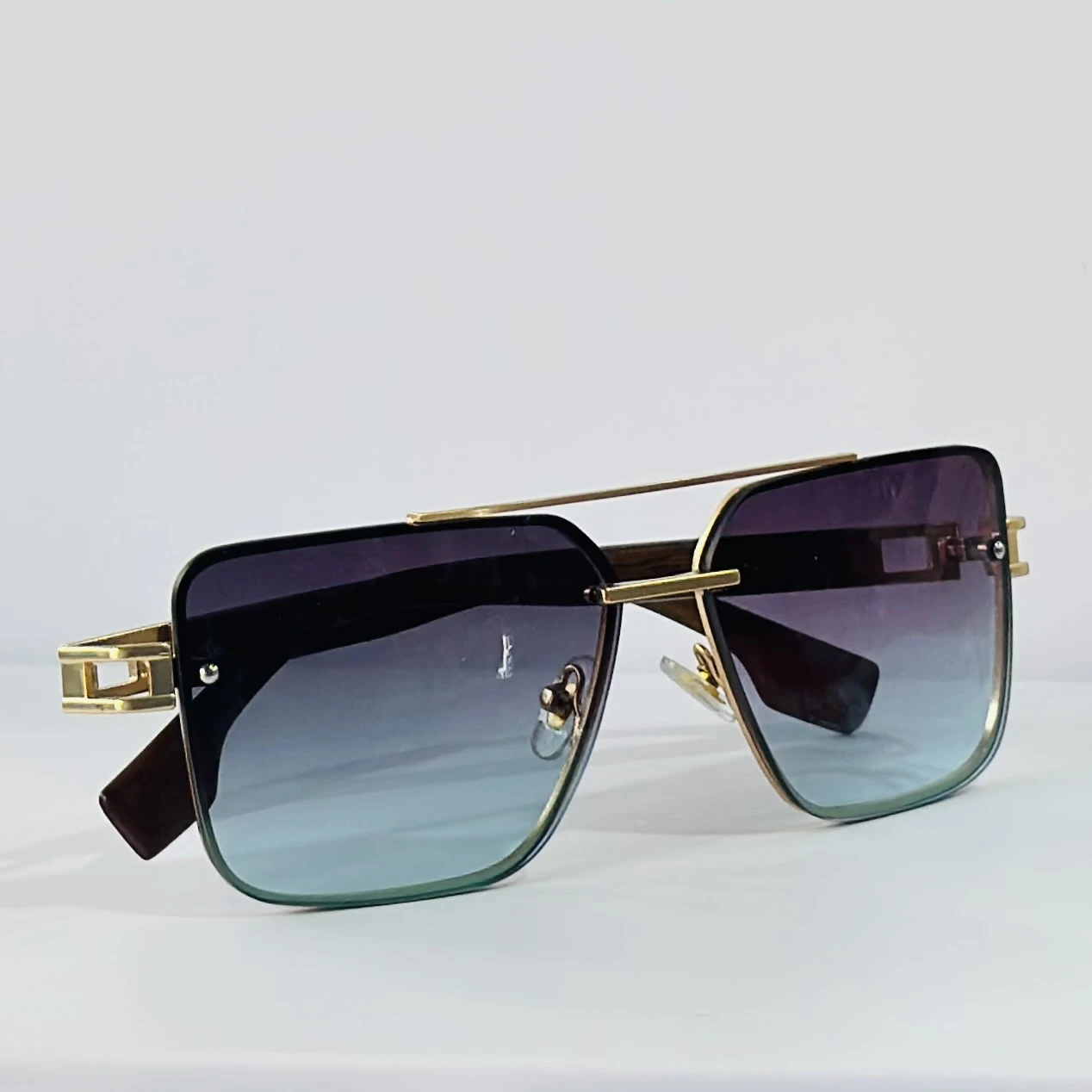 Pair of of aviator-style sunglasses with a gold-tone metal frame and blue gradient lenses.