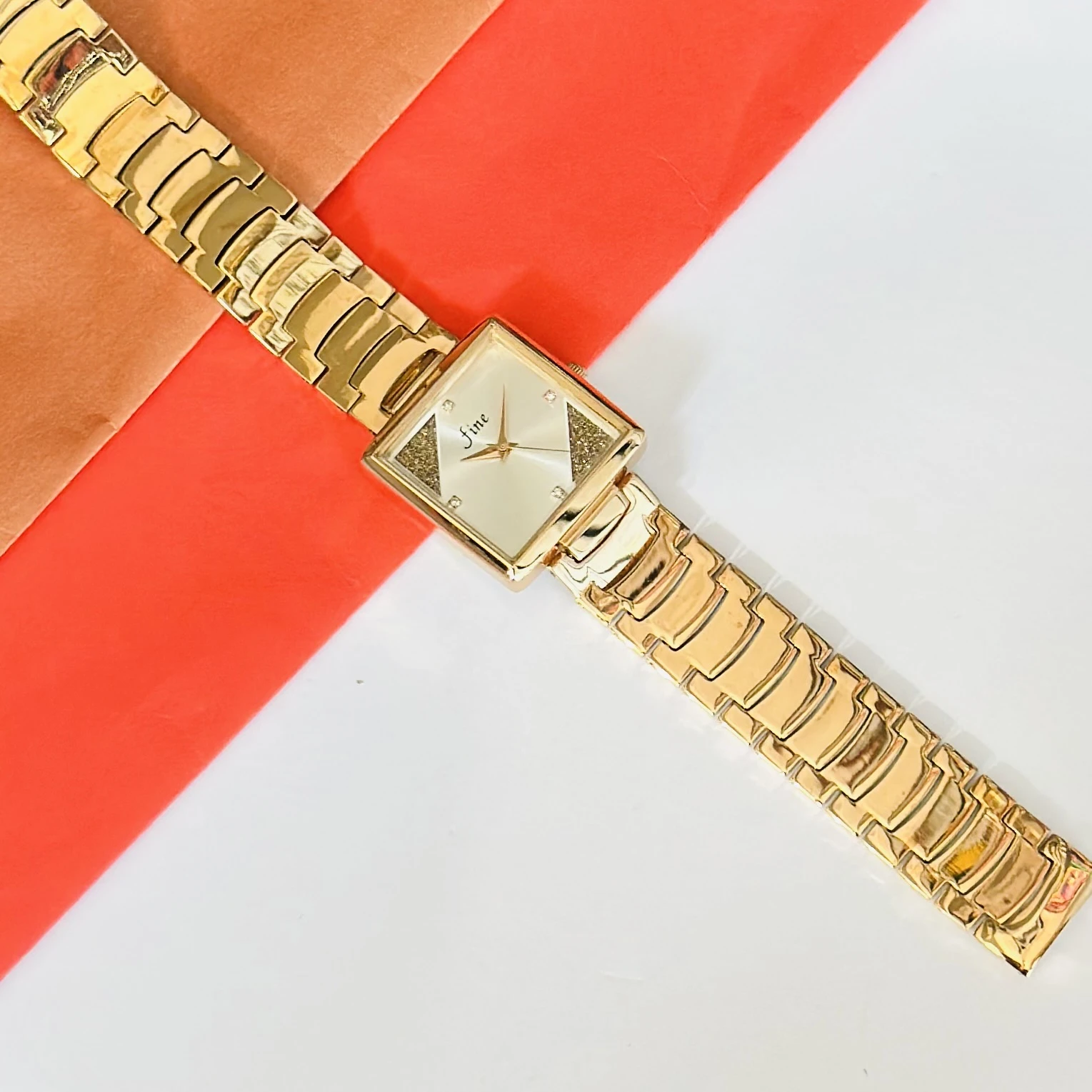 Gold -tone analog watch with a square dial and a metal strap.