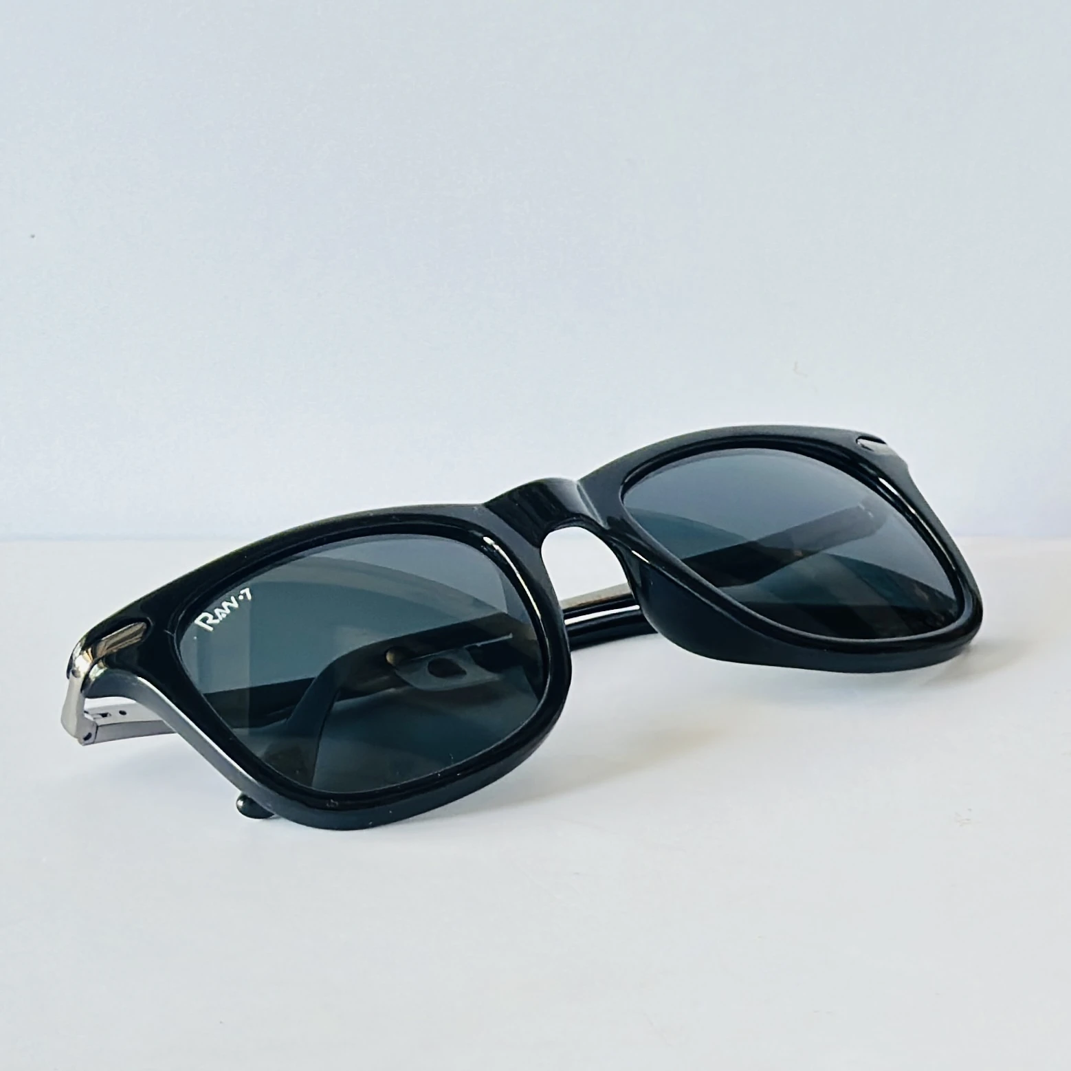 Black sunglasses appear to be similar to the iconic Ray-Ban Original Wayfarer.