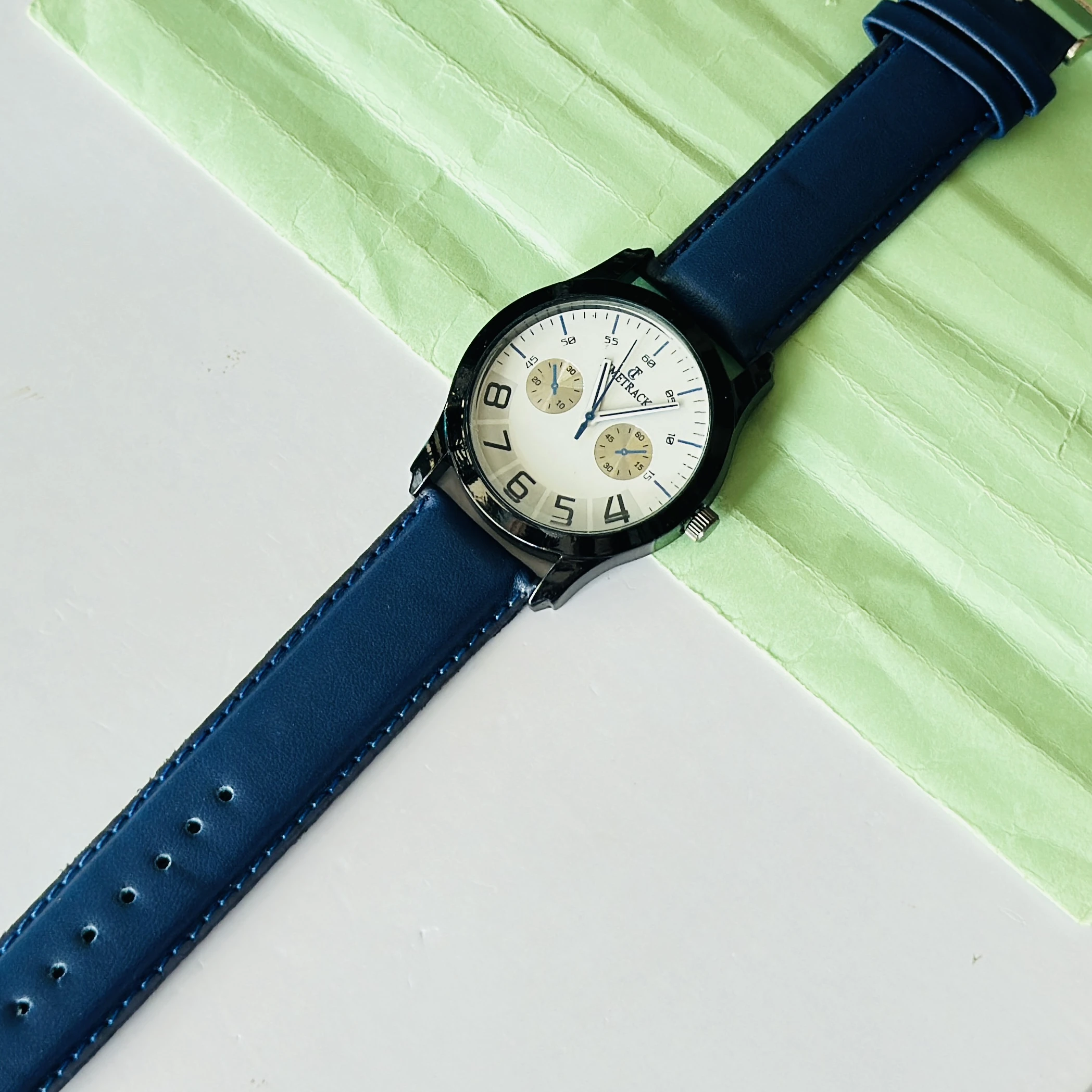 METRACK brand analog watch with a blue leather strap and a white dial