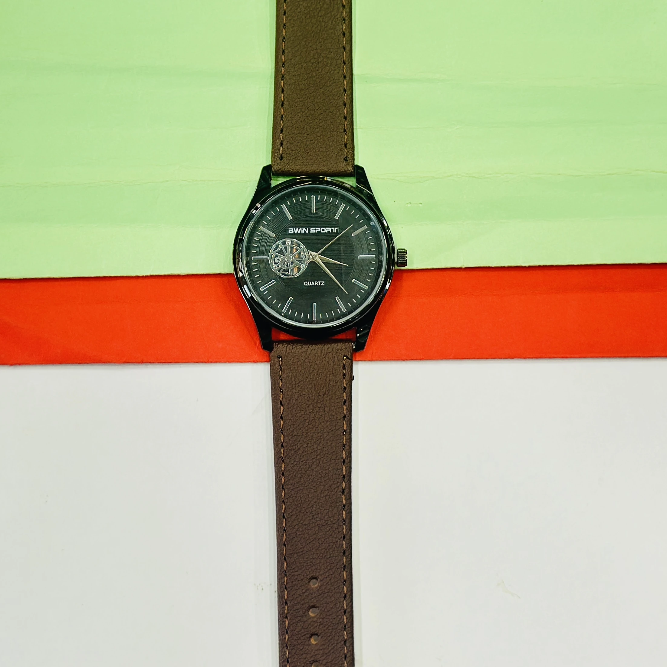 Quartz watch with a brown leather strap and a black dial.