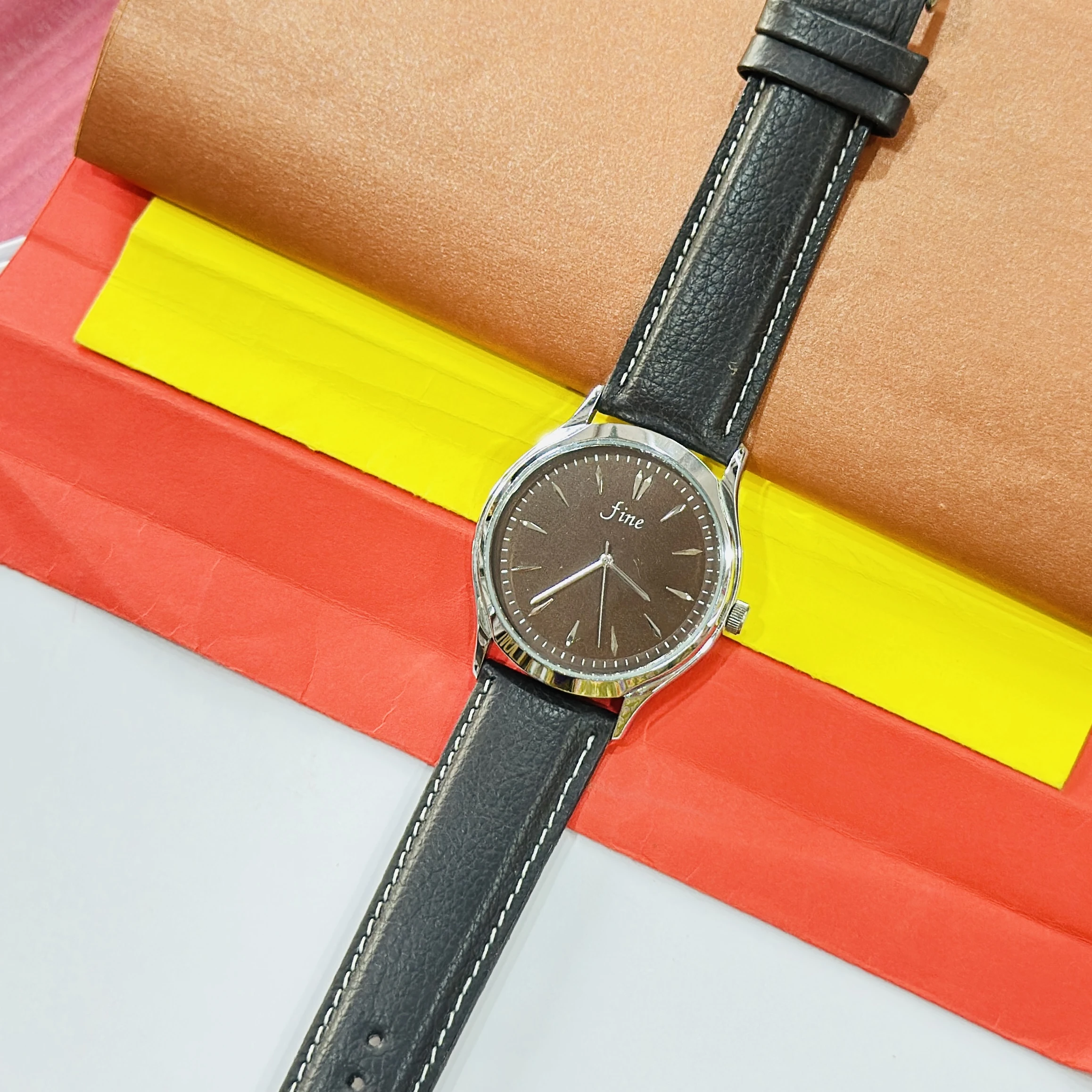 Fine" brand wristwatch featuring a black strap