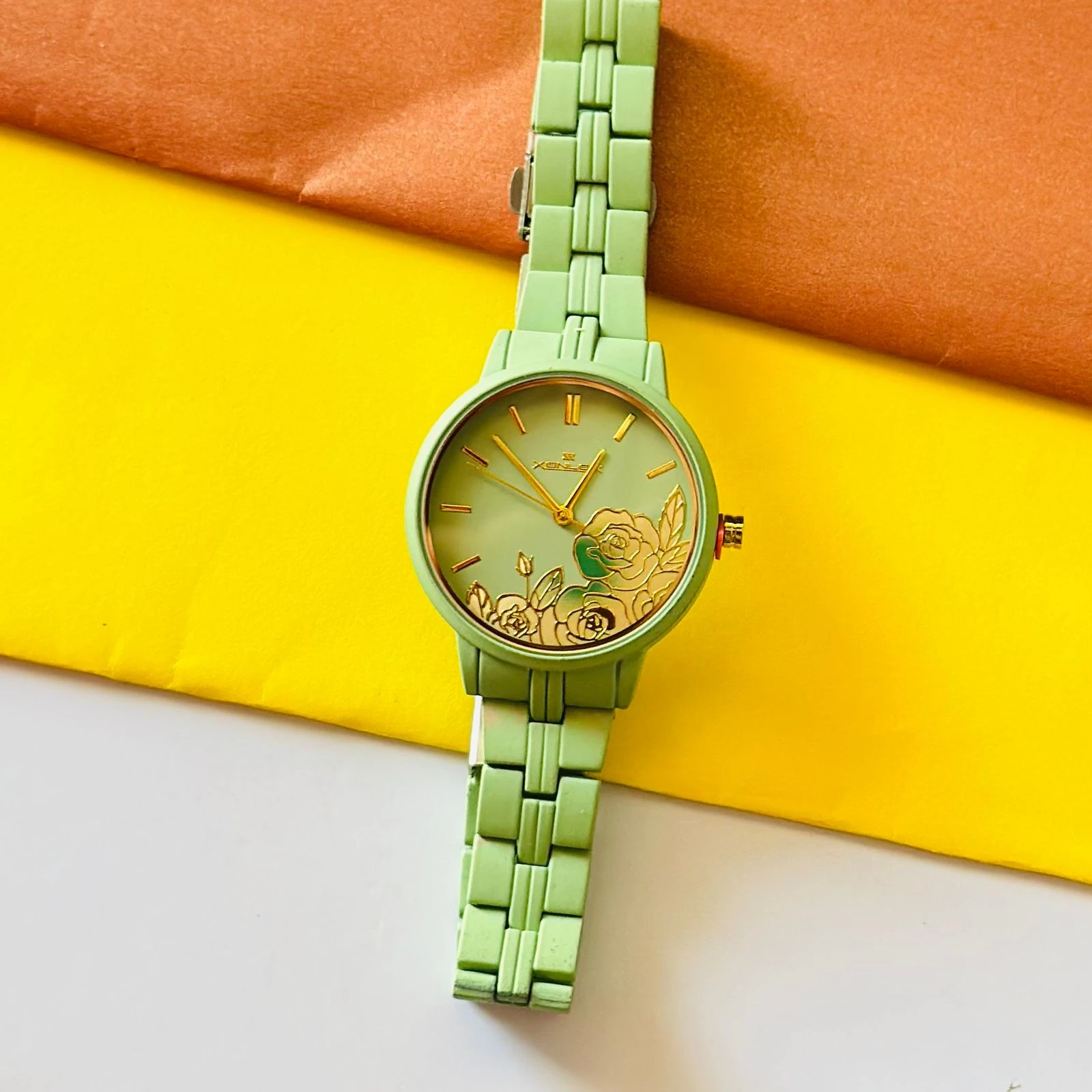 light green women's analog watch with a floral print on the dial and a link bracelet.