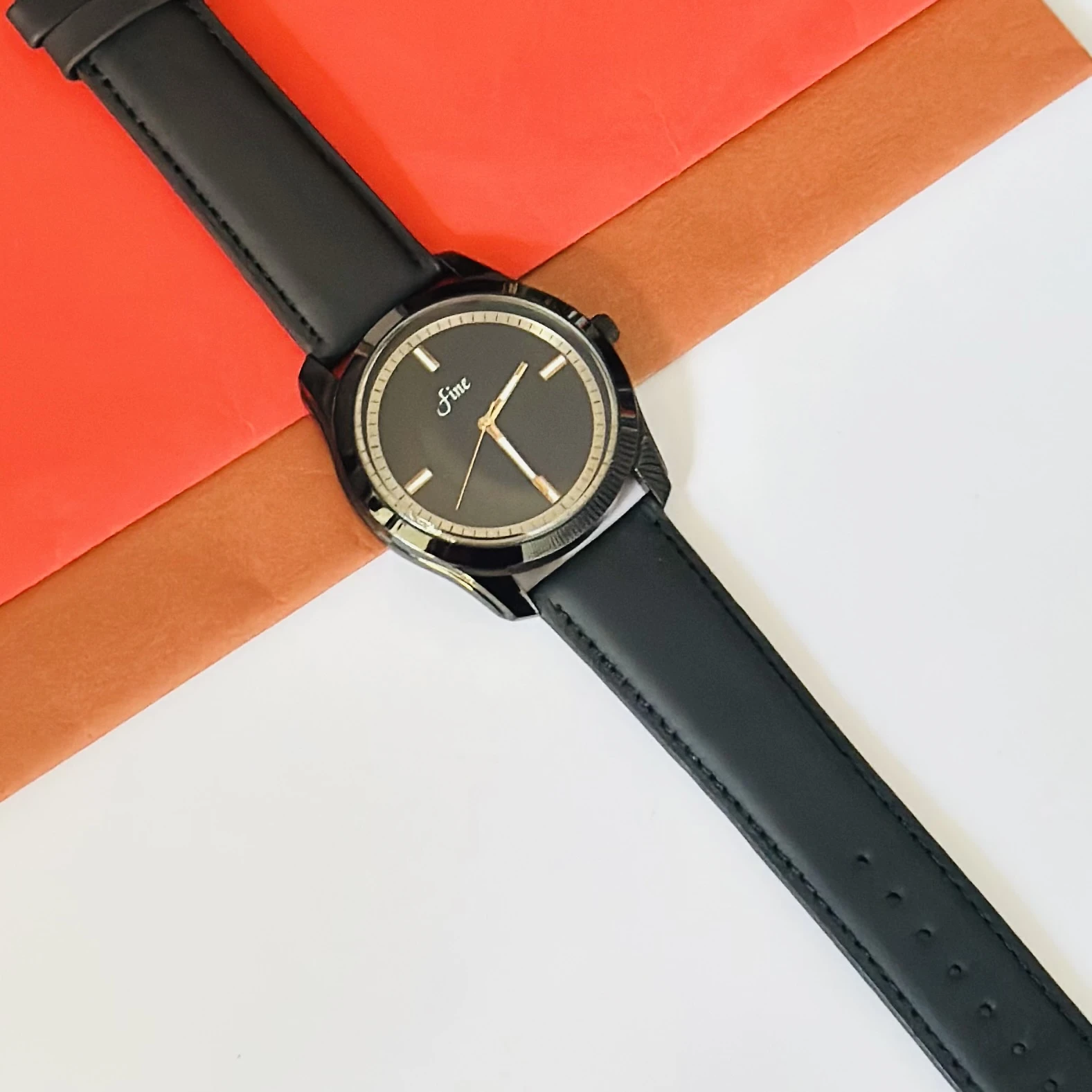 Black analog watch with a black leather or silicone strap.