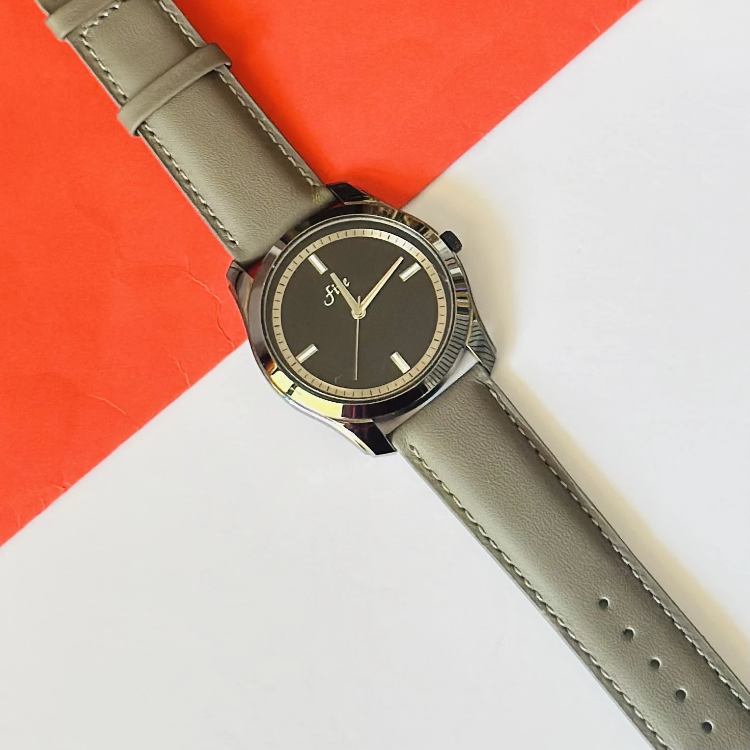 watch with a gray leather strap and a black dial.