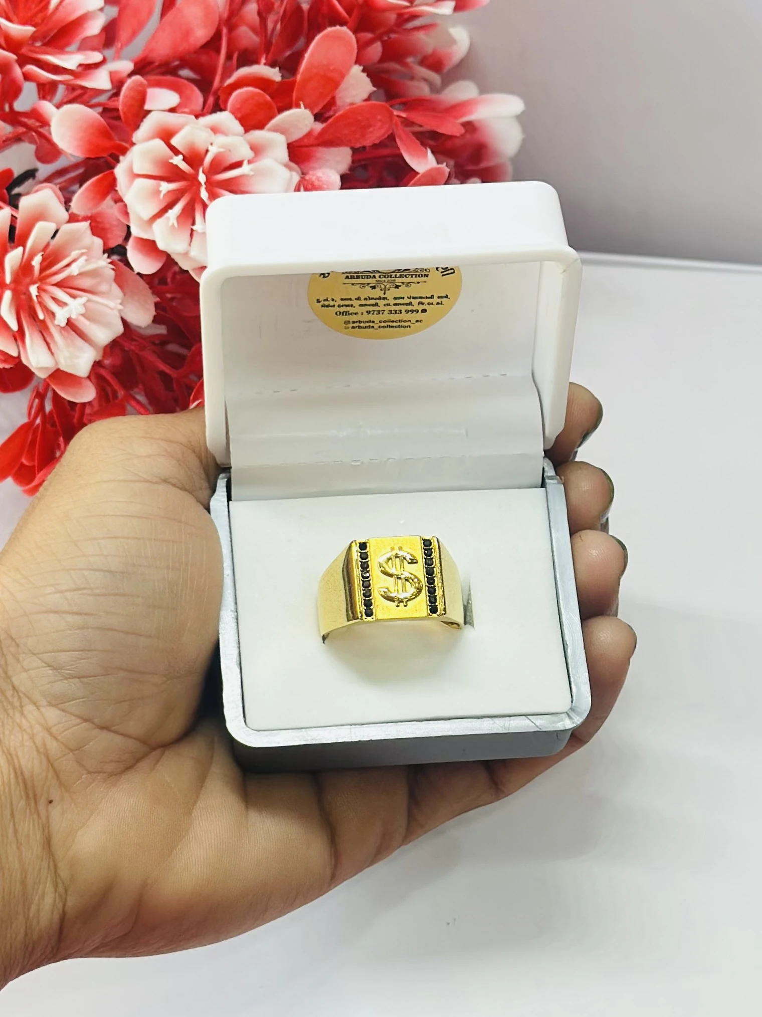 Gold toned men's ring featuring a dollar sign emblem and black accents.