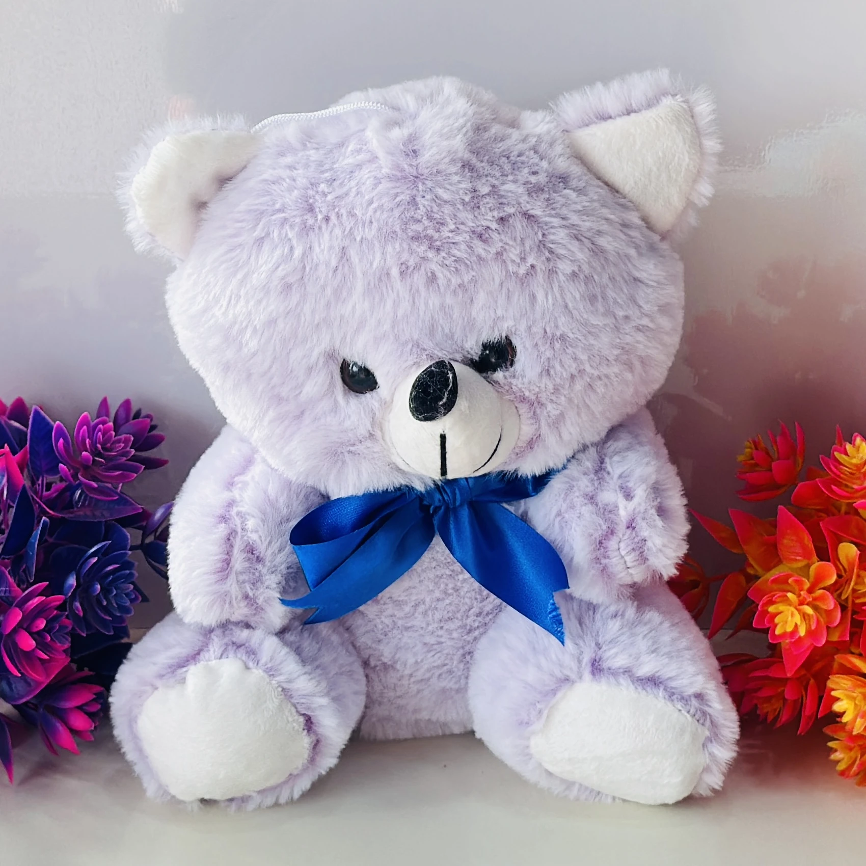 purple plush teddy bear with a blue ribbon
