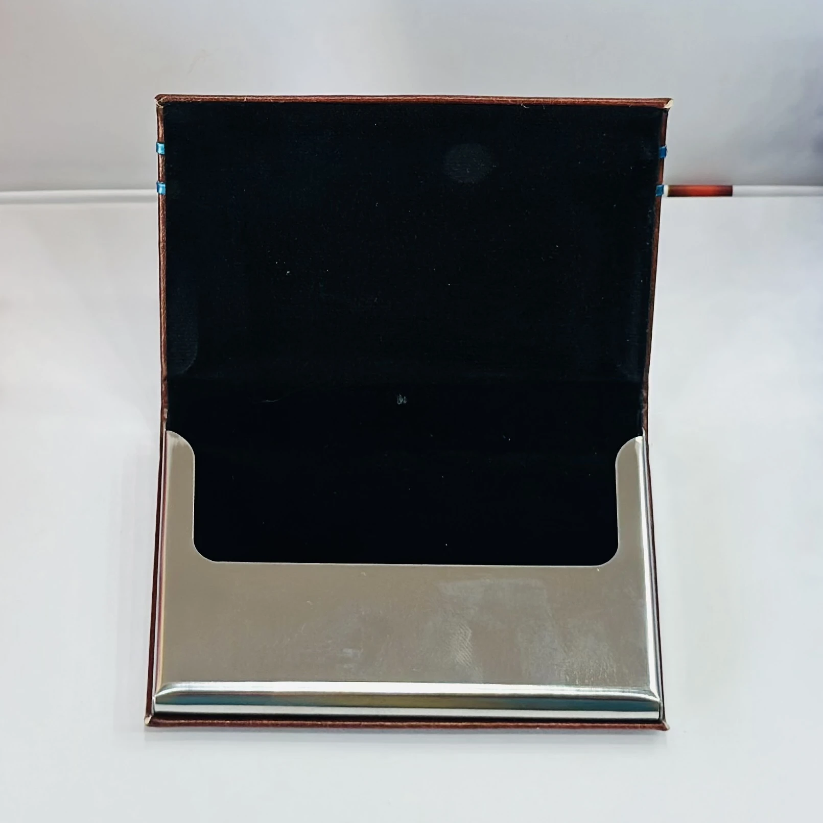 brown leather business card holder with blue metal accents.