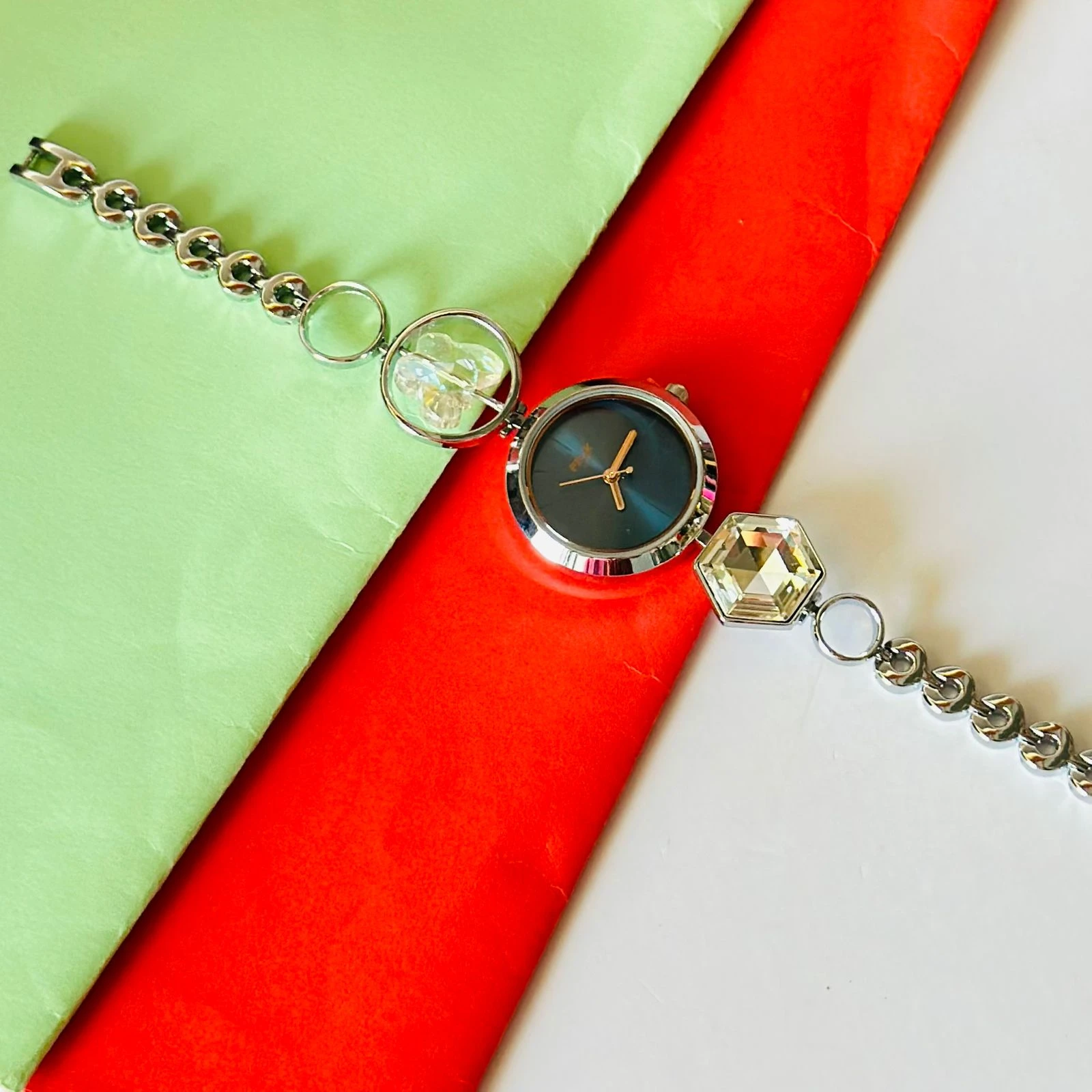 analog watch for women with a blue dial and a metal strap featuring crystal-studded geometric links.