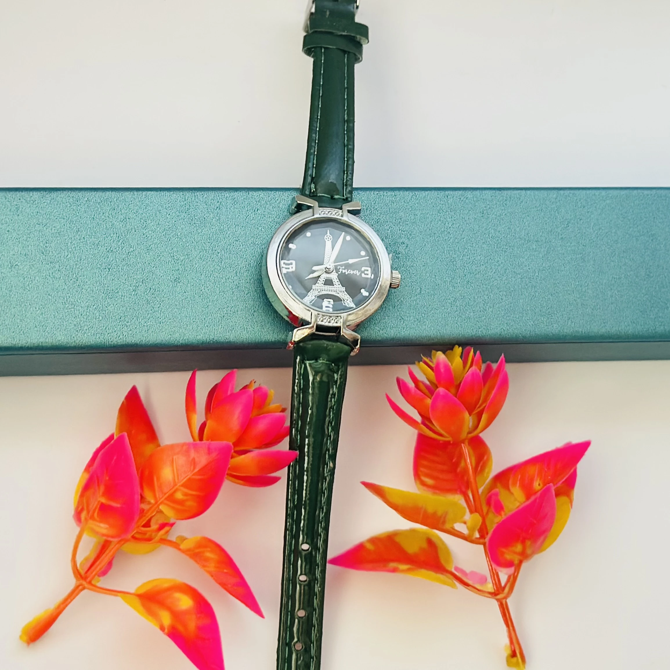 women's analog watch featuring an Eiffel Tower design and a green leather strap.