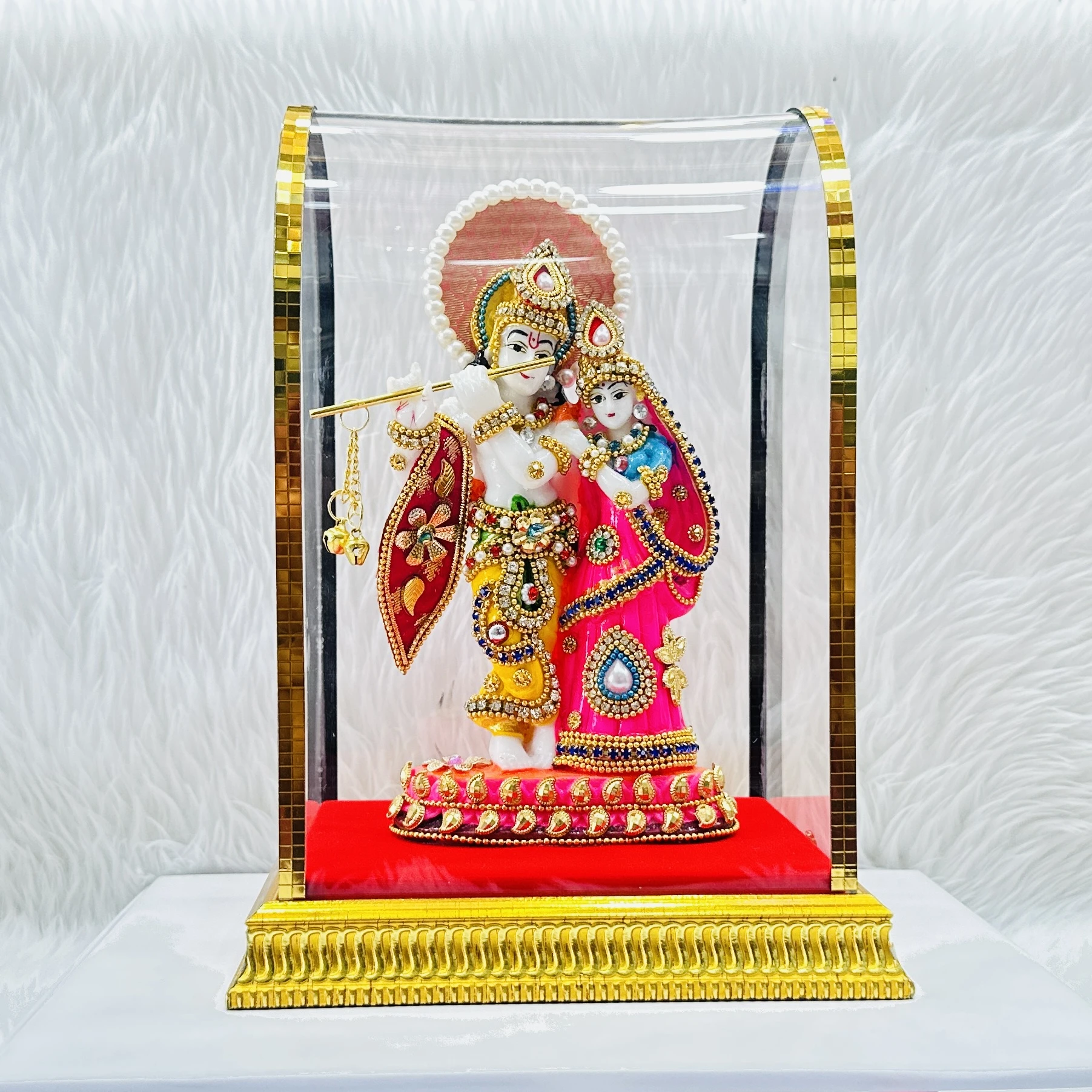 Radha Krishna statue enclosed in a protective glass dome.