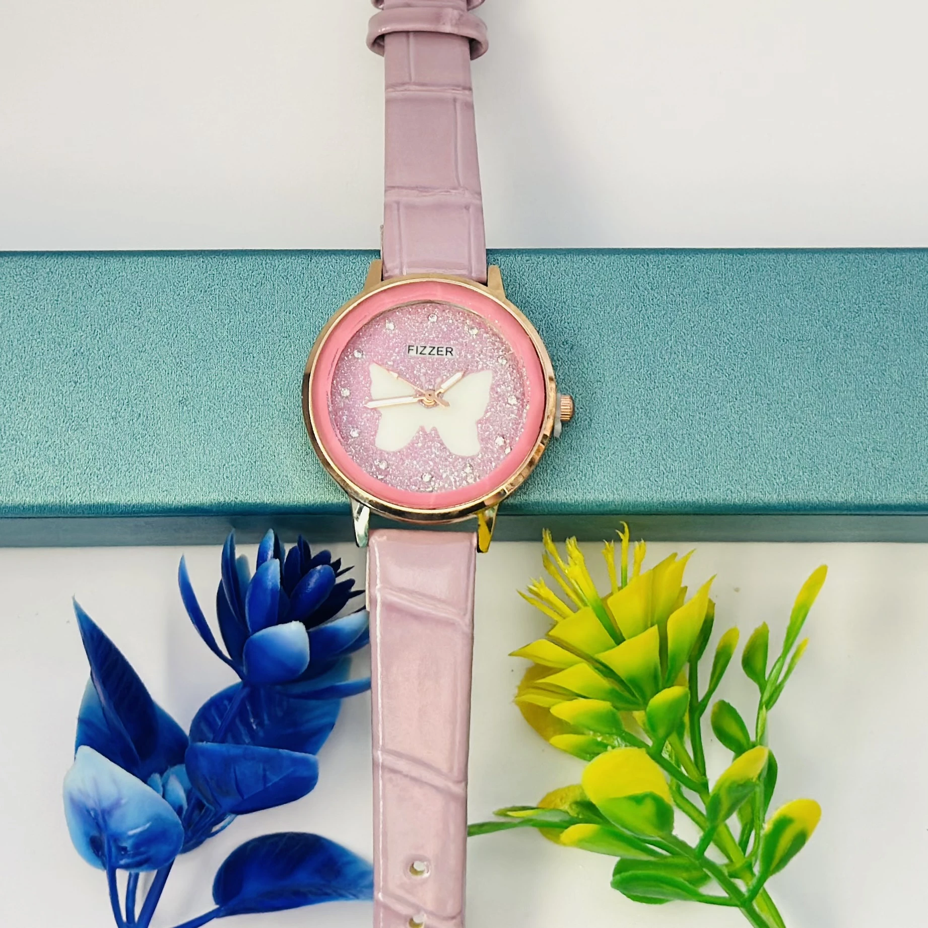 Pink analog watch with a butterfly design and a leather-style strap.