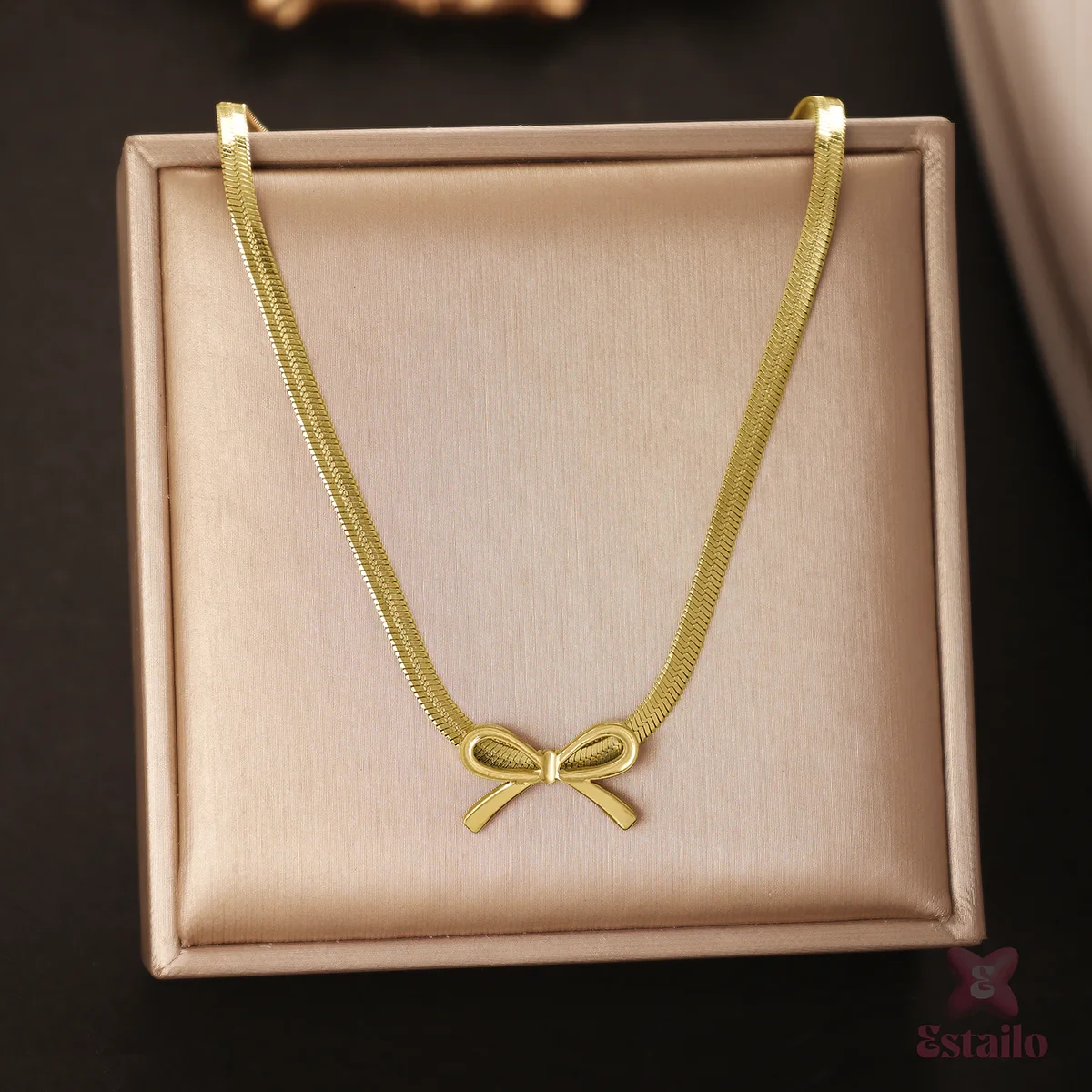 titanium steel necklace features a gold-plated herringbone chain and a bow-shaped pendant.