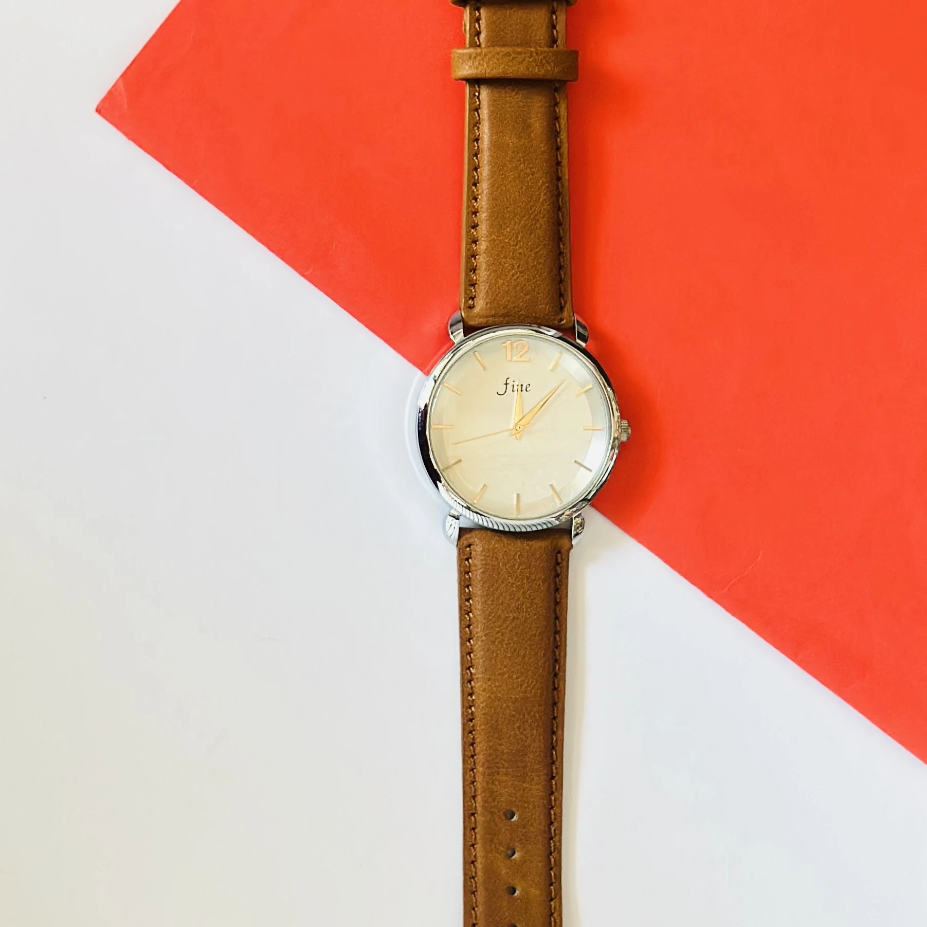 minimalist analog watch with a white dial, gold-tone case, and a brown leather strap