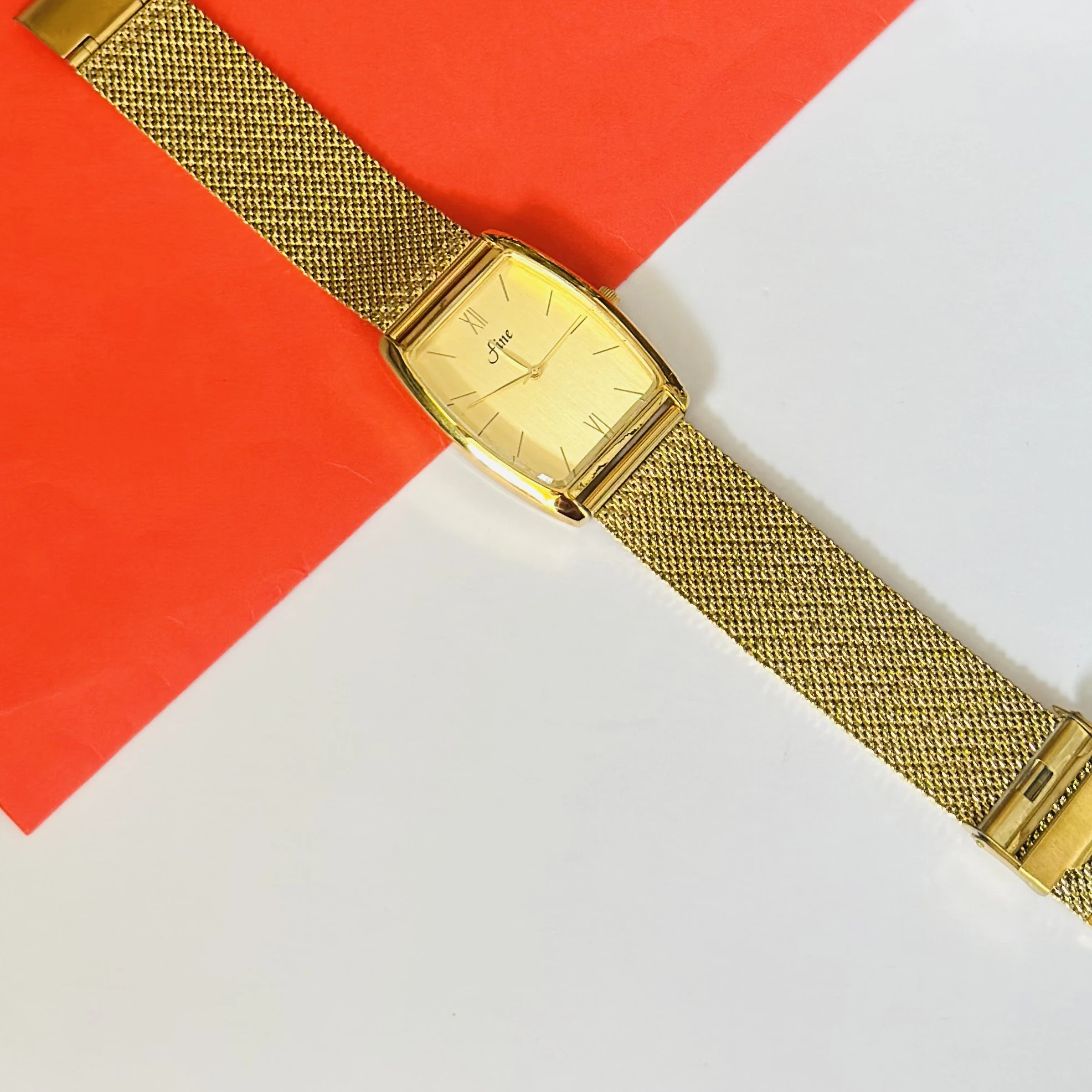 Gold -plated quartz analogue watch with a mesh strap.