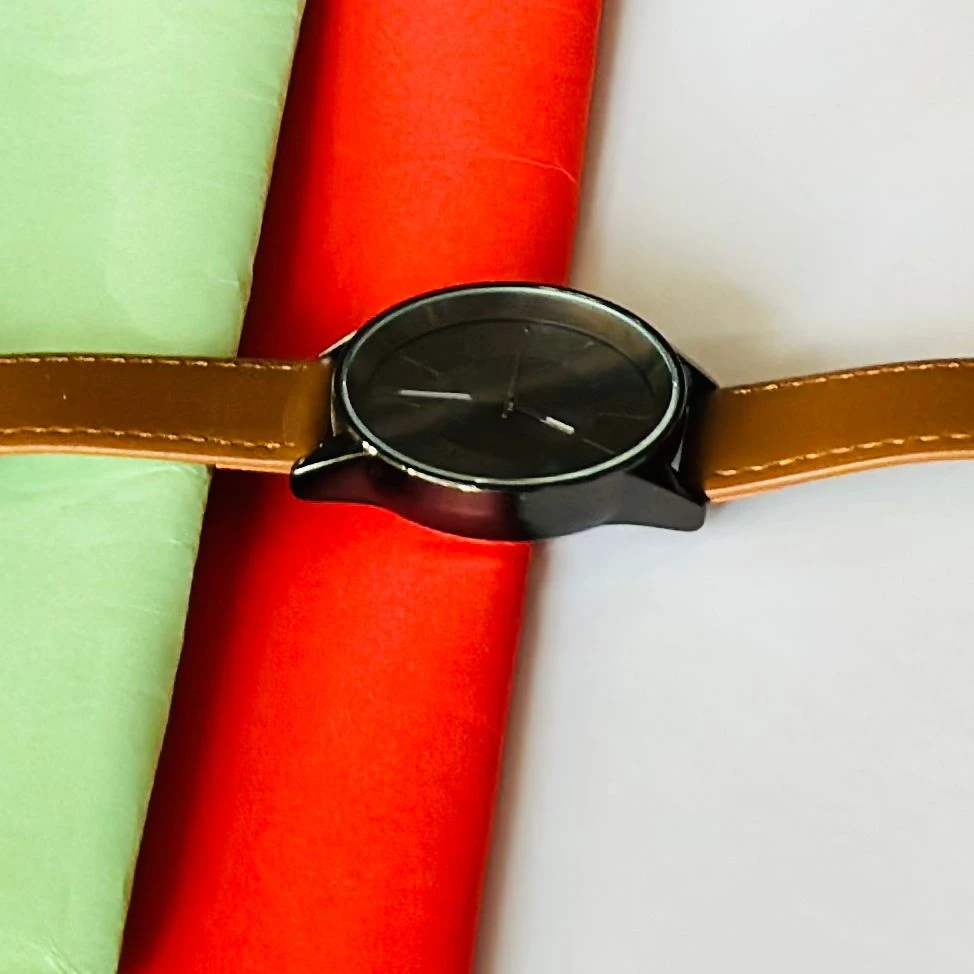 round analog watch with a brown leather strap