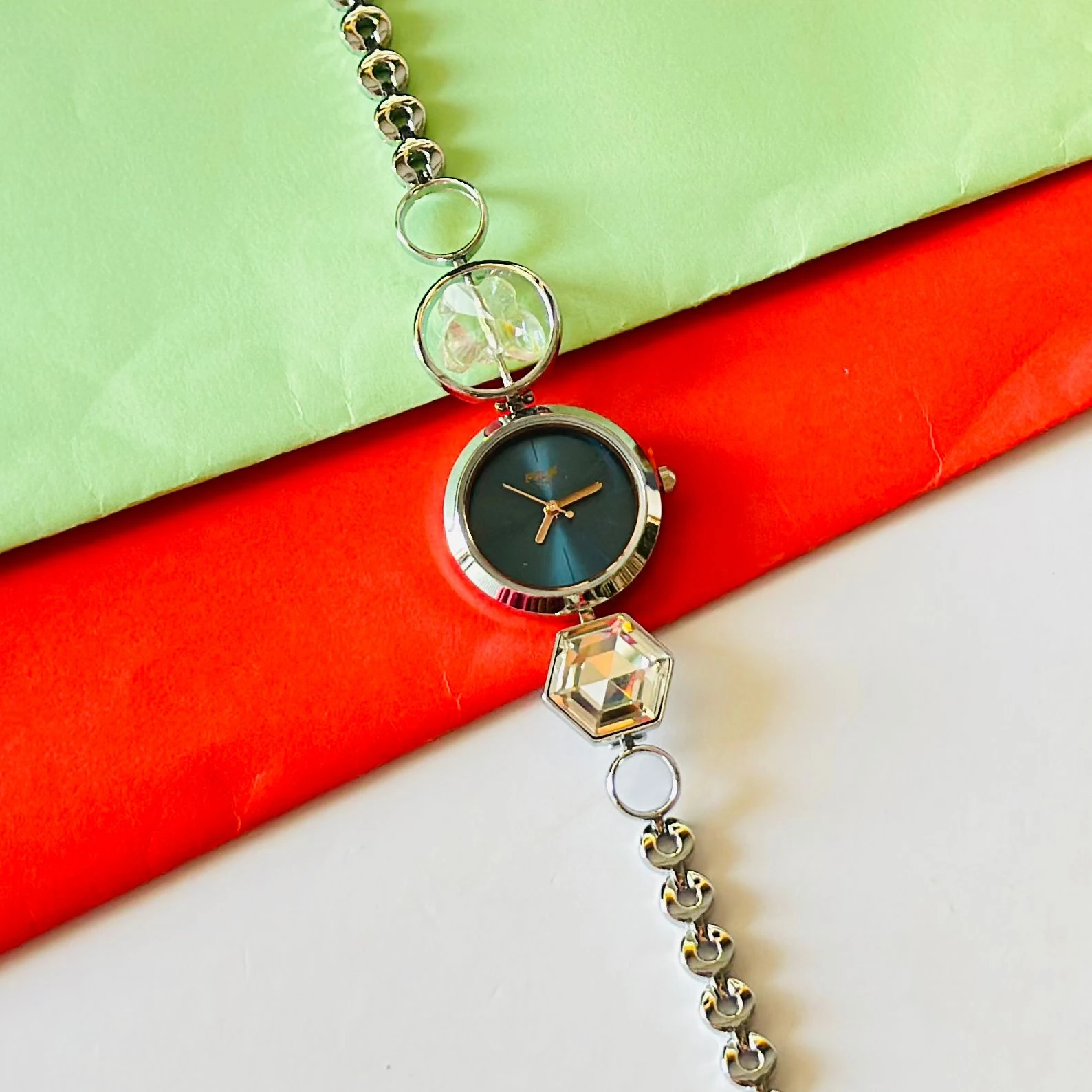 analog watch for women with a blue dial and a metal strap featuring crystal-studded geometric links.