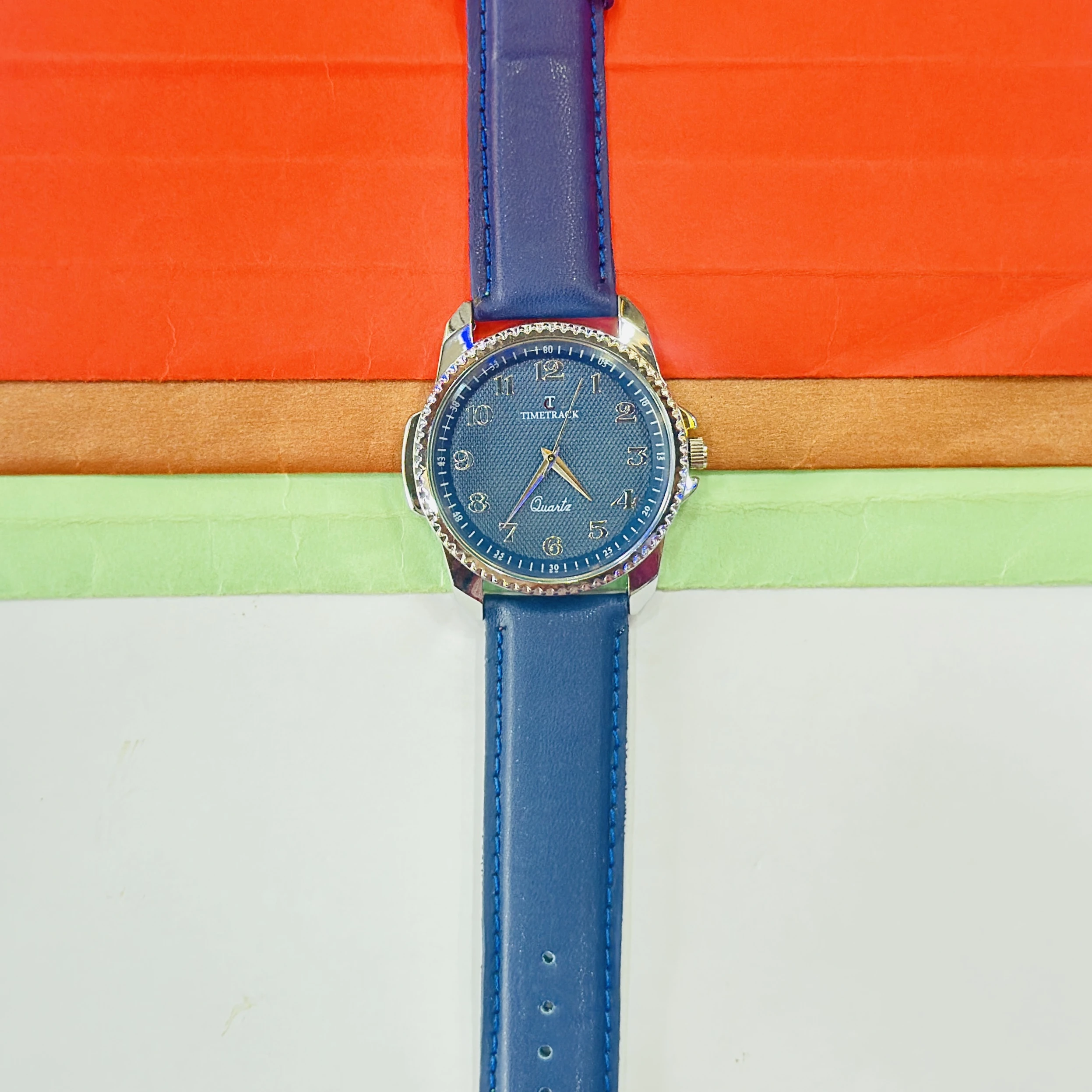 quartz analog watch features a blue dial and a matching navy blue leather strap