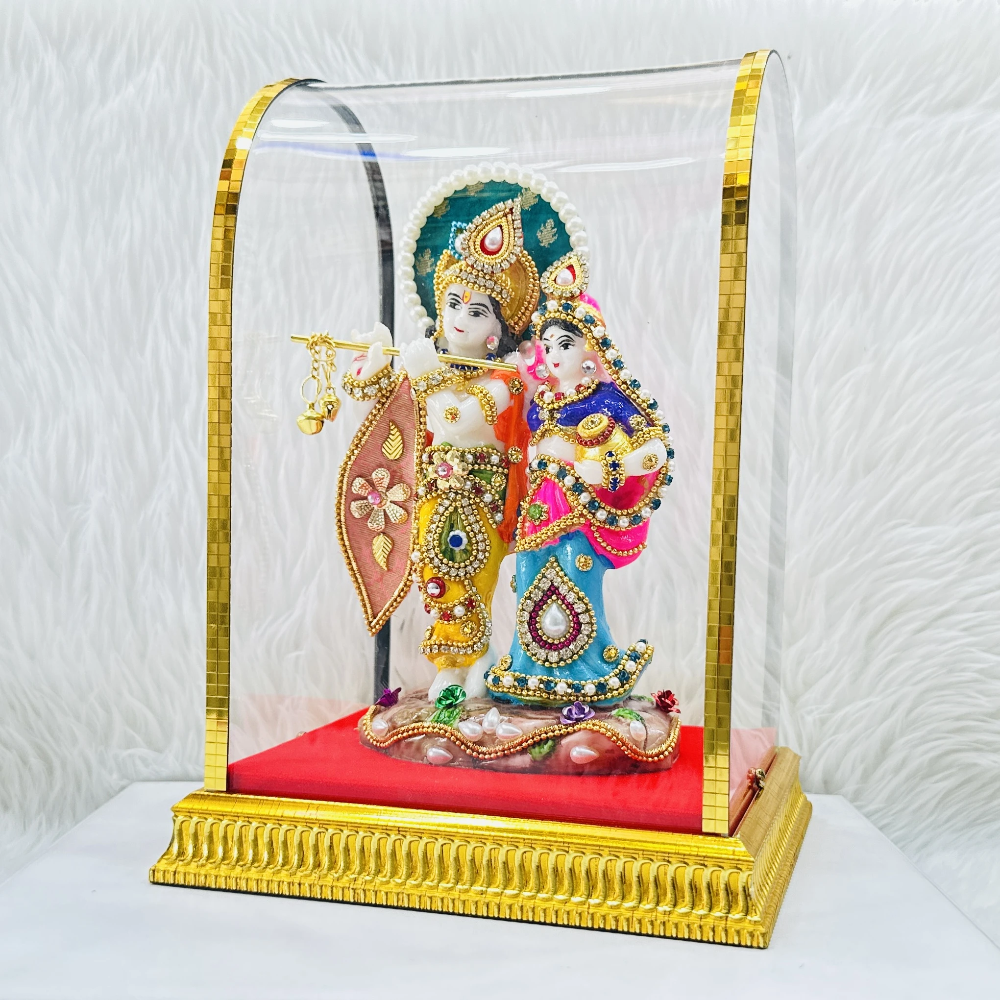 Radha Krishna statue enclosed in a protective glass dome.