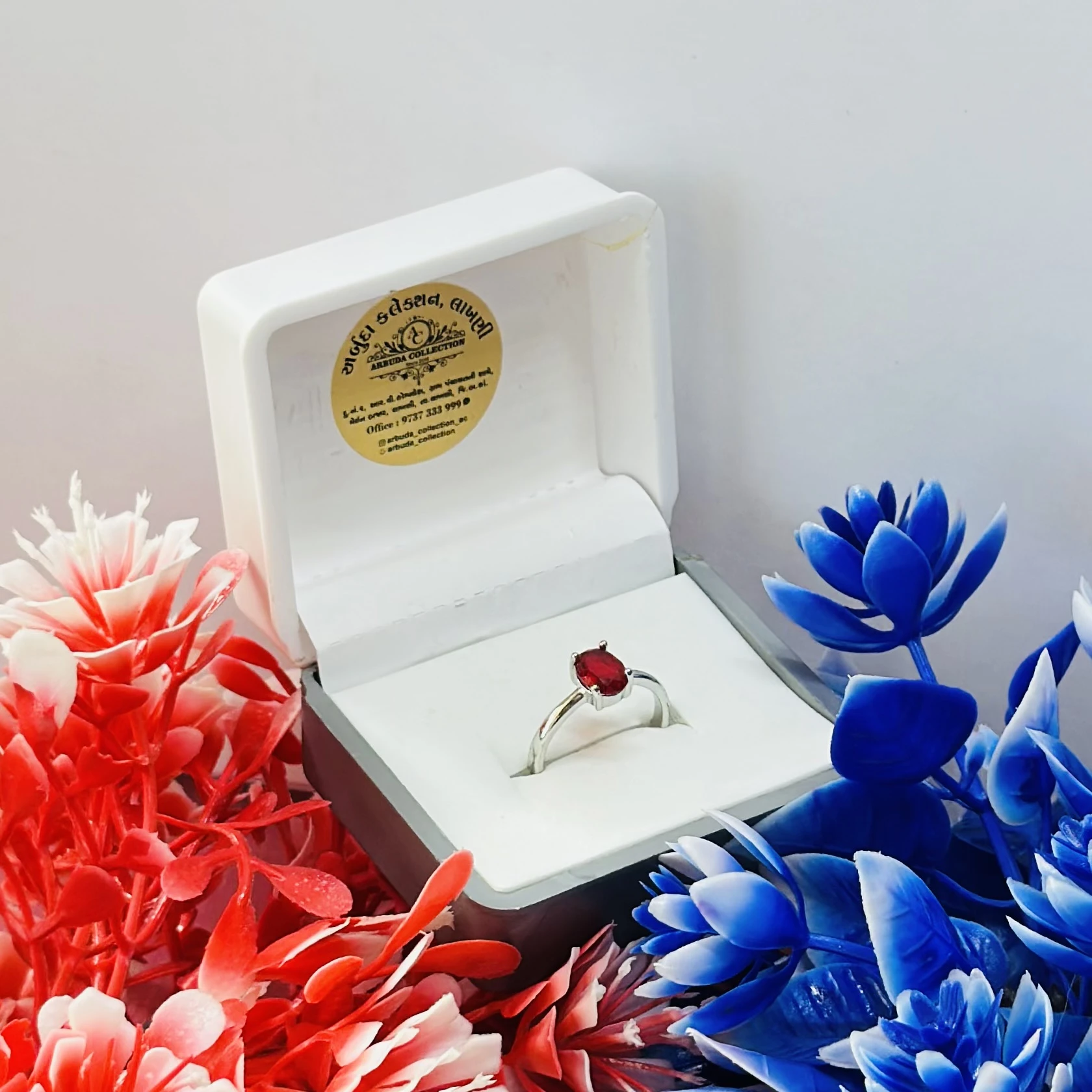 white gold or silver solitaire ring with an oval-cut ruby gemstone.