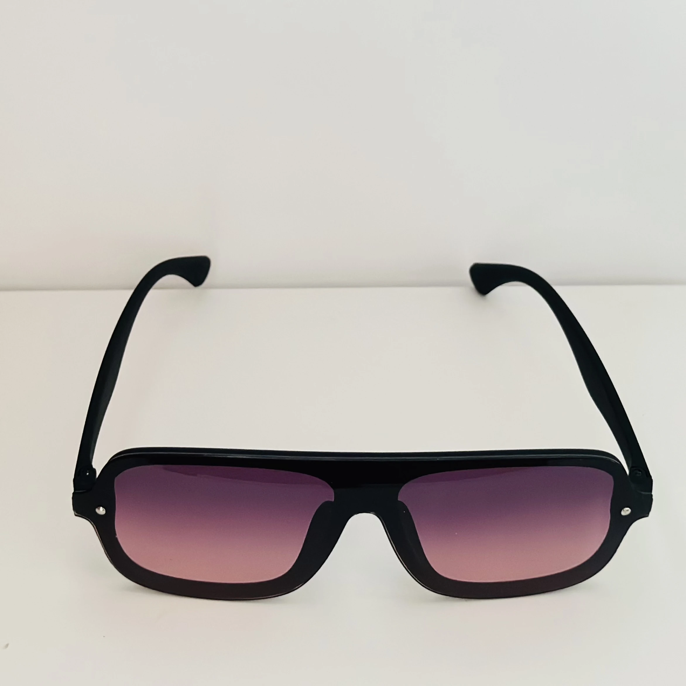 Black frame aviator-style sunglasses with pink gradient lenses.
